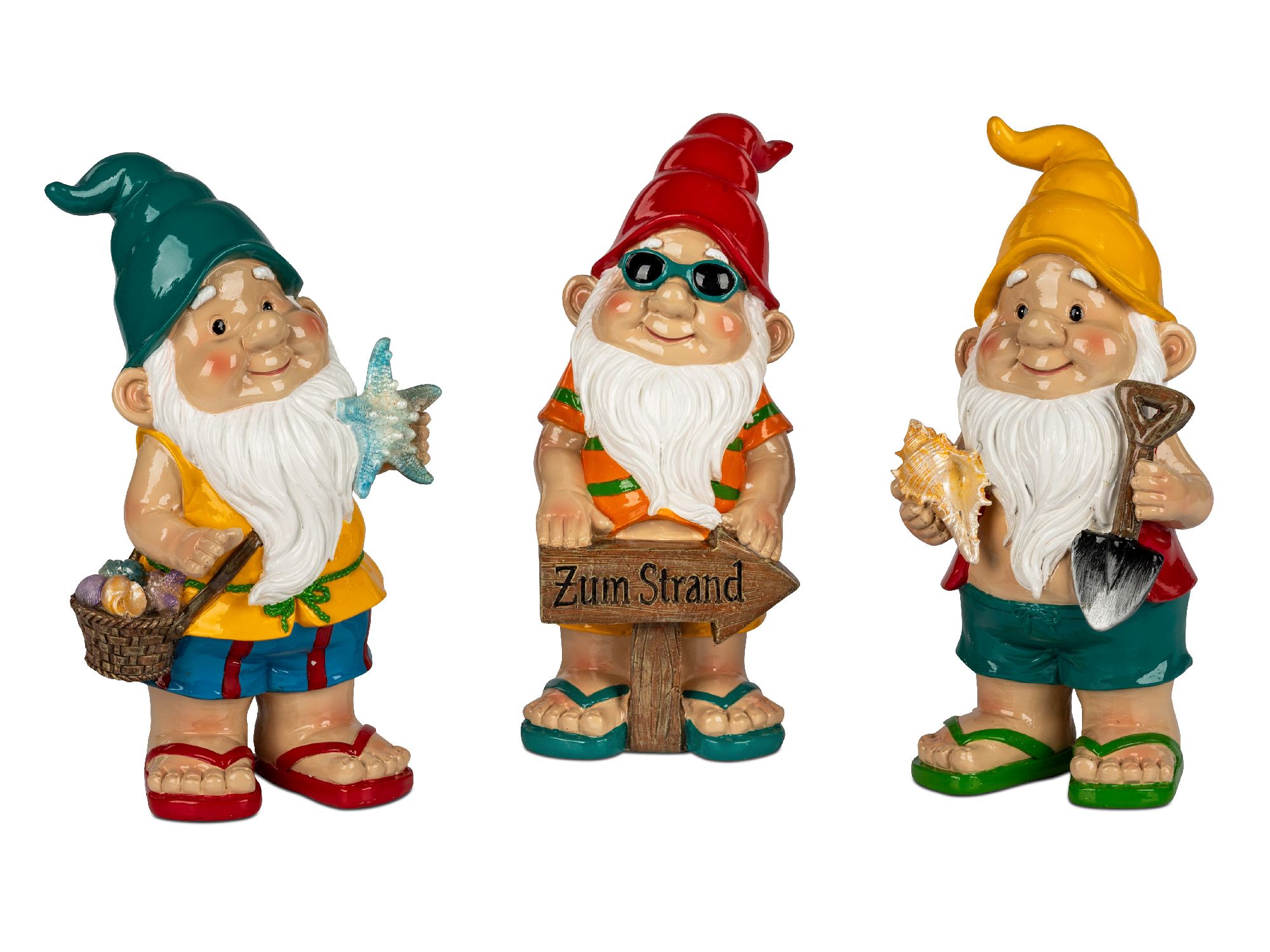 Drei bunte Gartenzwerge in Strandkleidung, einer mit einem Schild „Zum Strand“, einer mit einer Muschel und einer mit einer Schaufel.