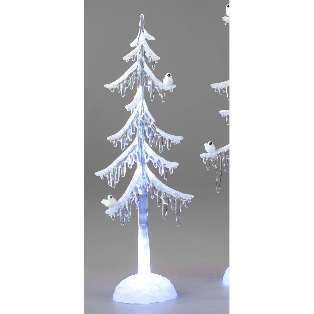 Ein künstlicher Weihnachtsbaum mit weißen Zweigen, Eiszapfen und kleinen Vögeln, beleuchtet von unte