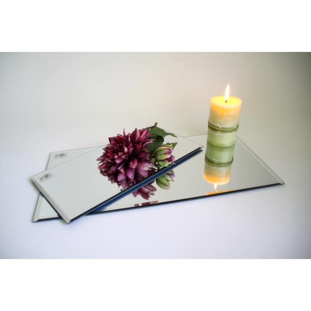 Drei Spiegel liegen auf einer Oberfläche, darauf eine Blume und eine brennende Kerze in einem grünen Halter.