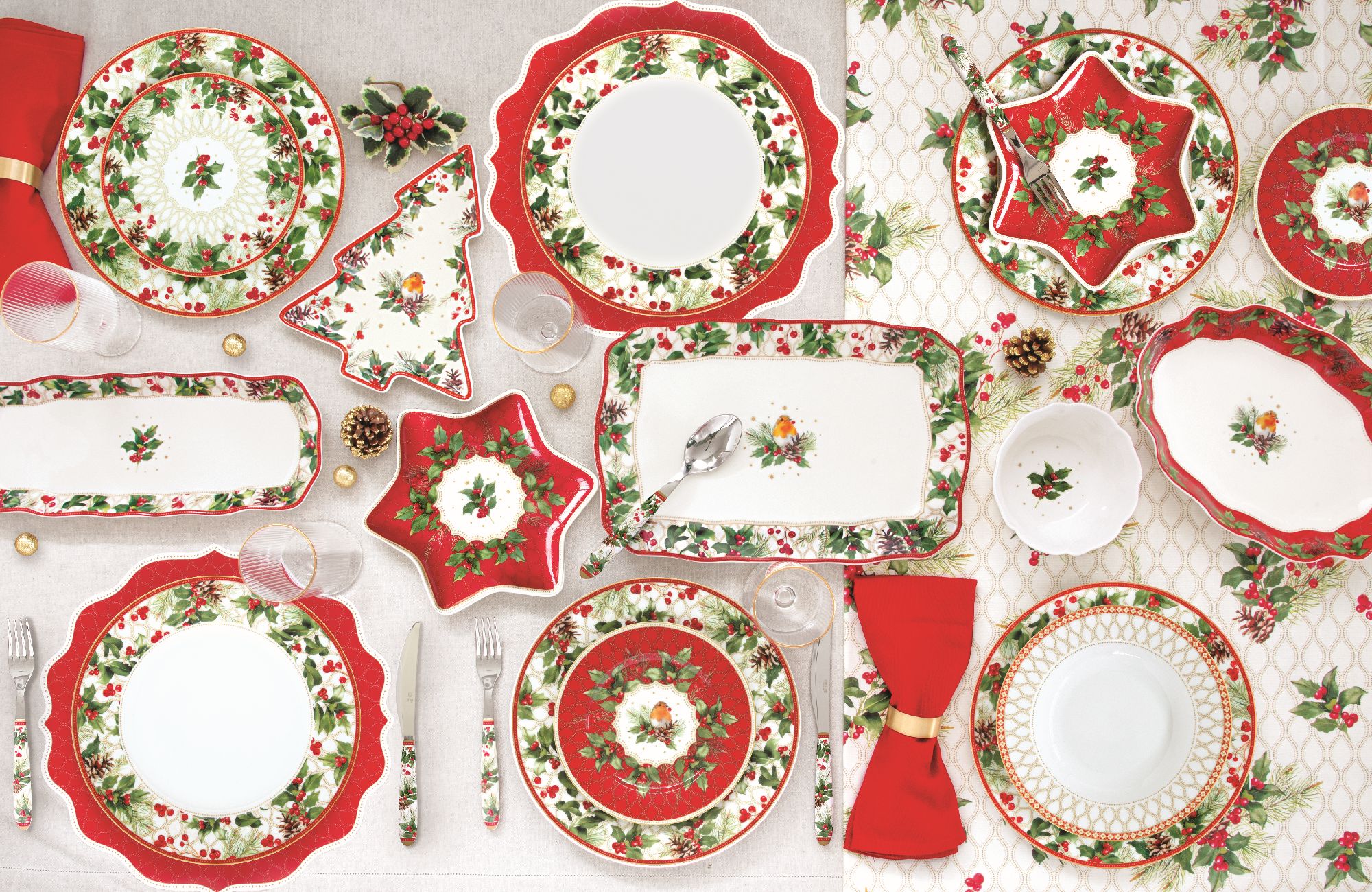 Tischgedeck mit verschiedenen Tellern, Schalen und Gläsern in Rot- und Grüntönen, dekoriert mit Weih