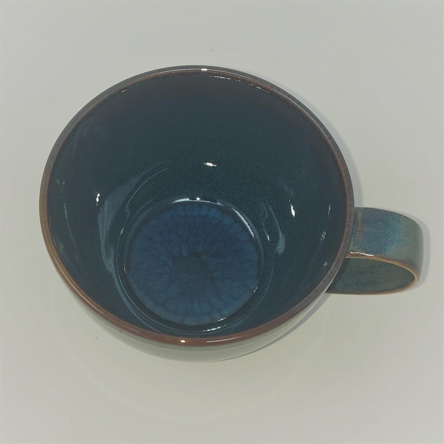 Blick auf eine dunkelblaue Tasse von oben, mit einem glatten, glänzenden Innenraum und einem Henkel an der Seite.