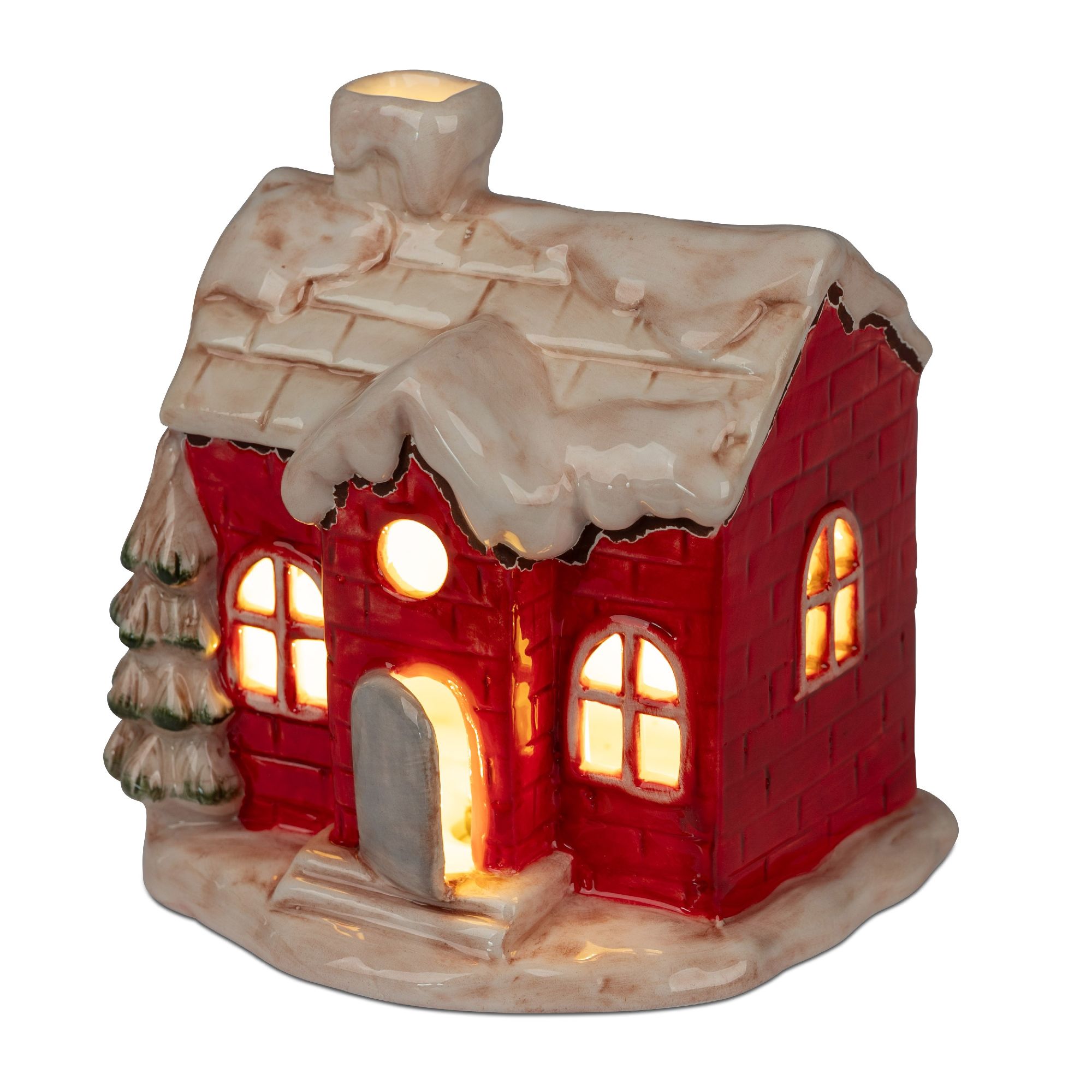 Rotes, keramisches Haus mit schneebedecktem Dach, beleuchtet von innen. Neben dem Haus steht ein kleiner, grüner Tannenbaum.
