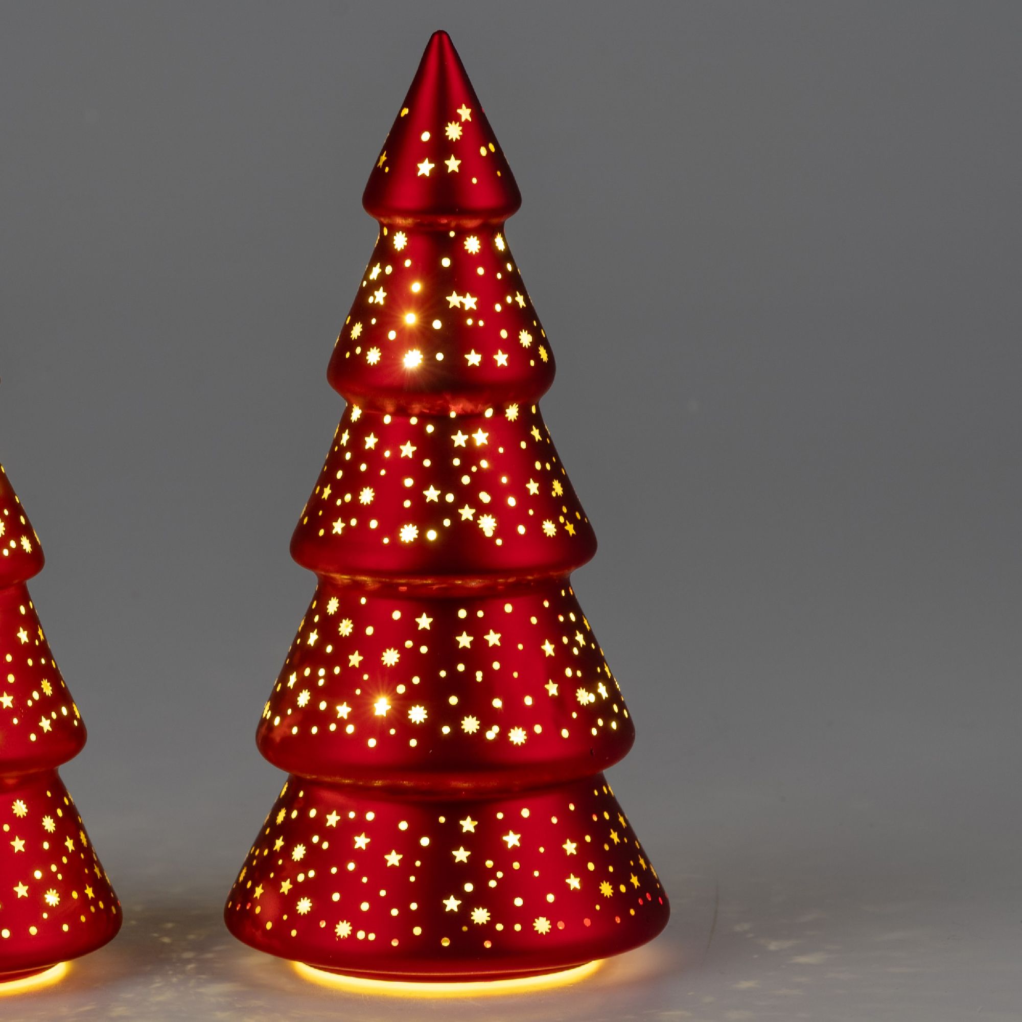 Roter Weihnachtsbaum aus Metall mit mehreren Stufen, verziert mit kleinen Löchern in Sternform, die