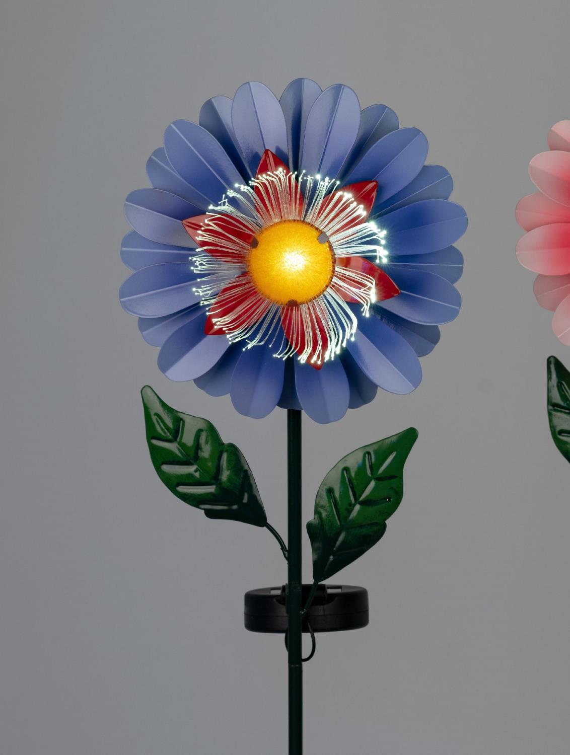 Bunte Blume aus Kunststoff mit blauen Blütenblättern, rotem Inneren und gelber Mitte, auf einem grünen Stiel mit Blättern.