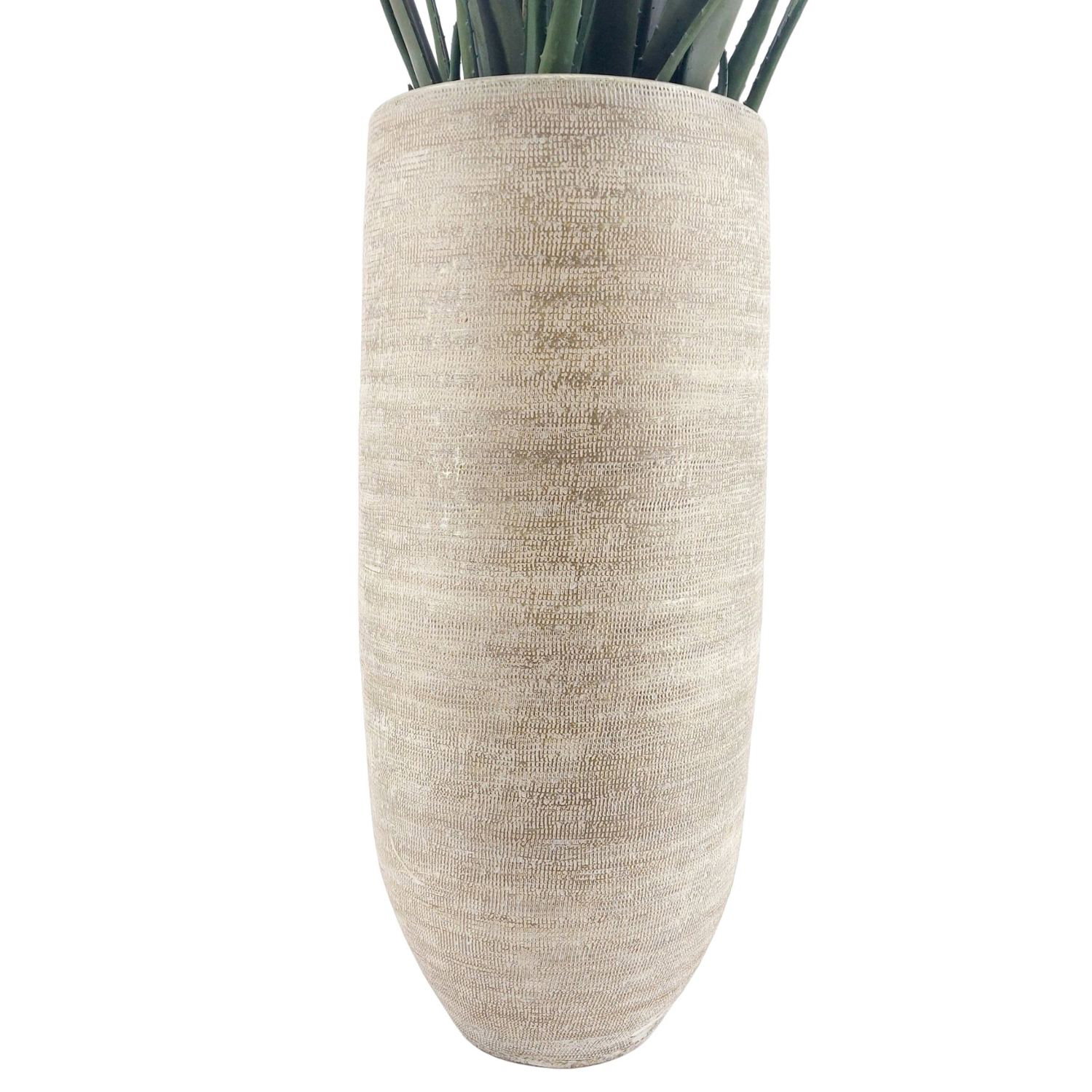 Hohe beige Vase mit strukturierter Oberfläche, oben ragen grüne Stängel heraus