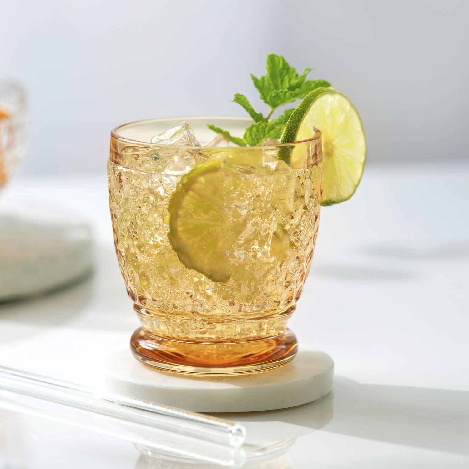 Ein Glas mit einem Getränk, Eiswürfeln, Limettenscheibe und Minze