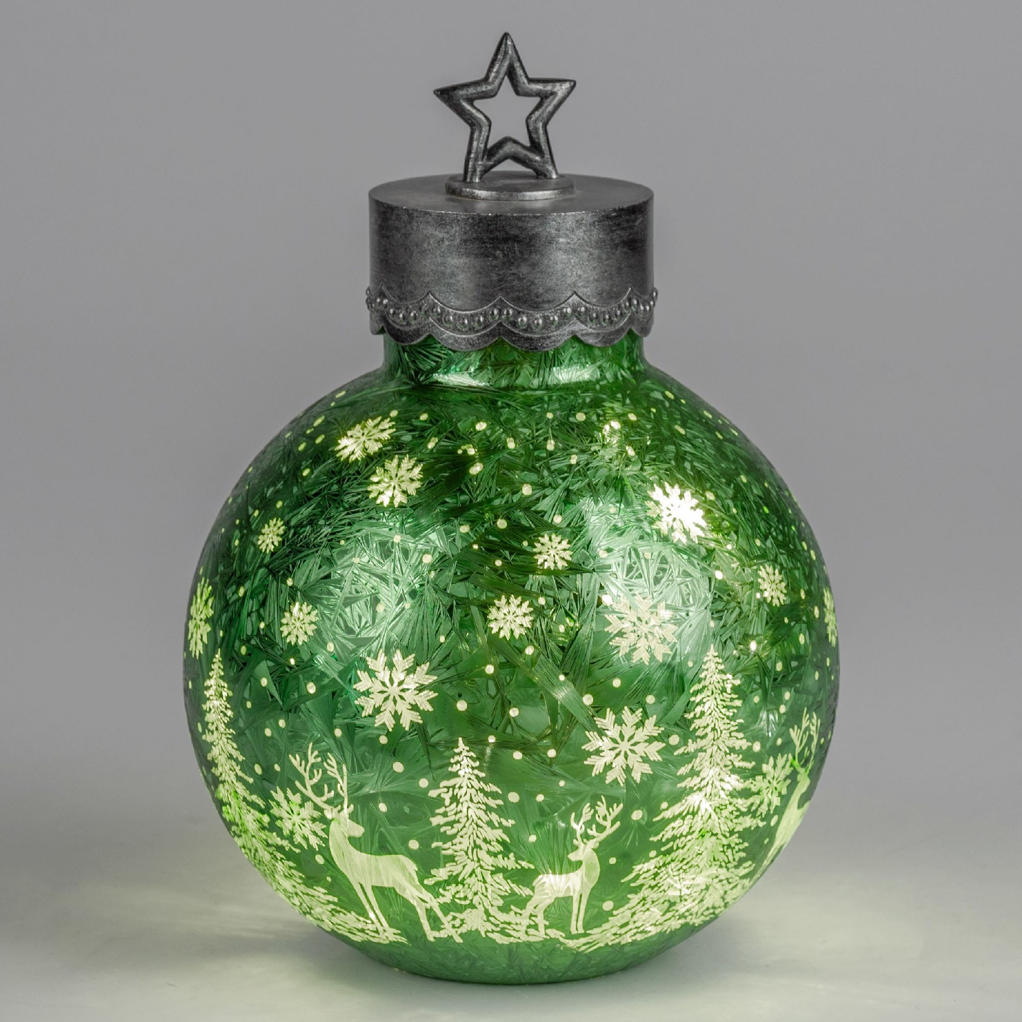 Grüne Weihnachtskugel mit Schneeflocken, Tannenbäumen und Rehen, oben mit einem silbernen Stern verz