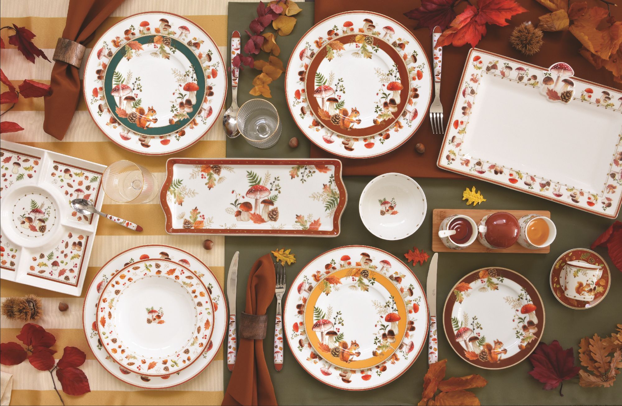 Tischgedeck mit verschiedenen Tellern, Gläsern und Besteck, dekoriert mit herbstlichen Motiven und b