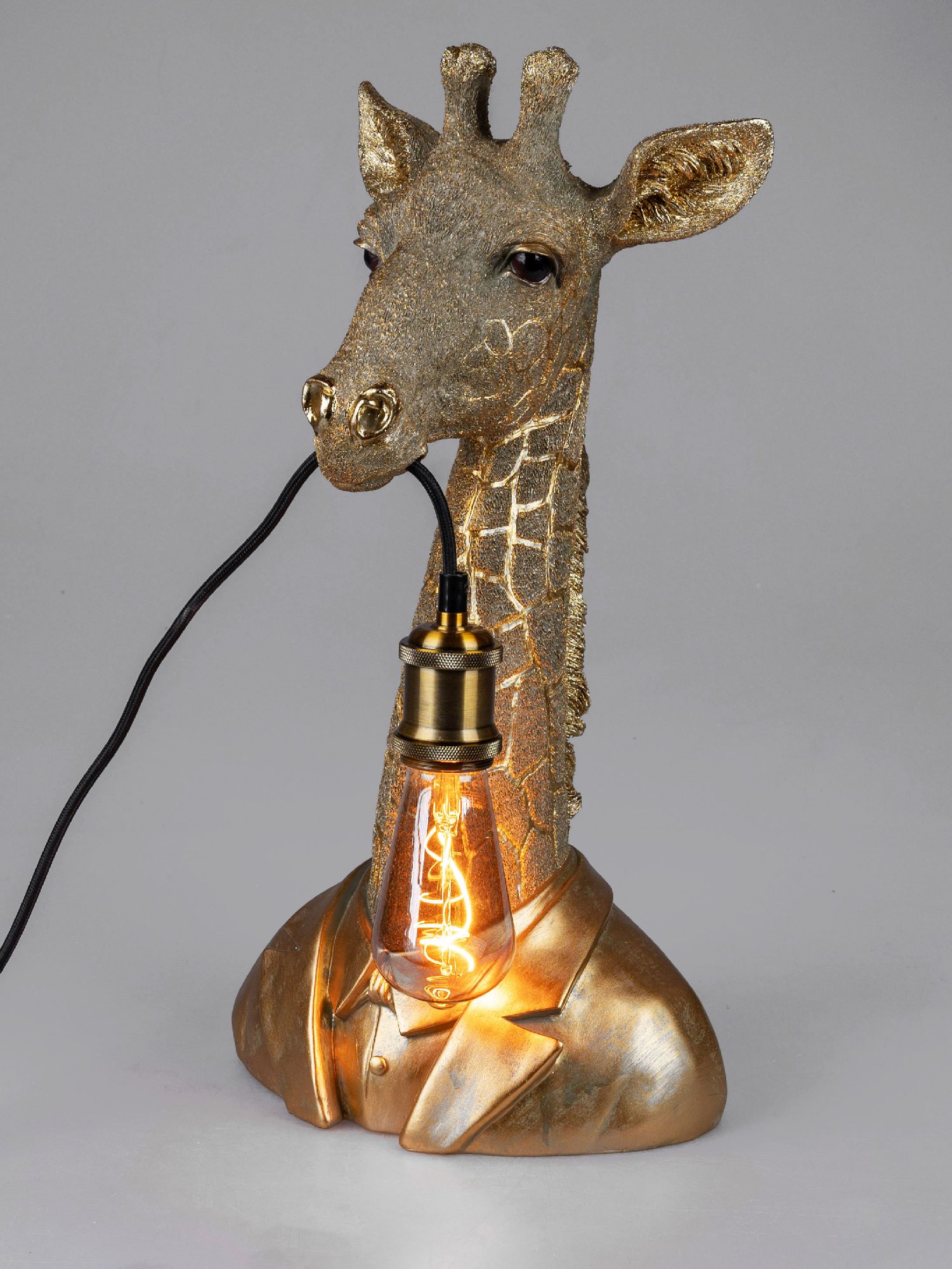 Tischlampe in Form eines Giraffenkopfes mit goldener Oberfläche und Glühbirne im Hals, auf grauem Hi