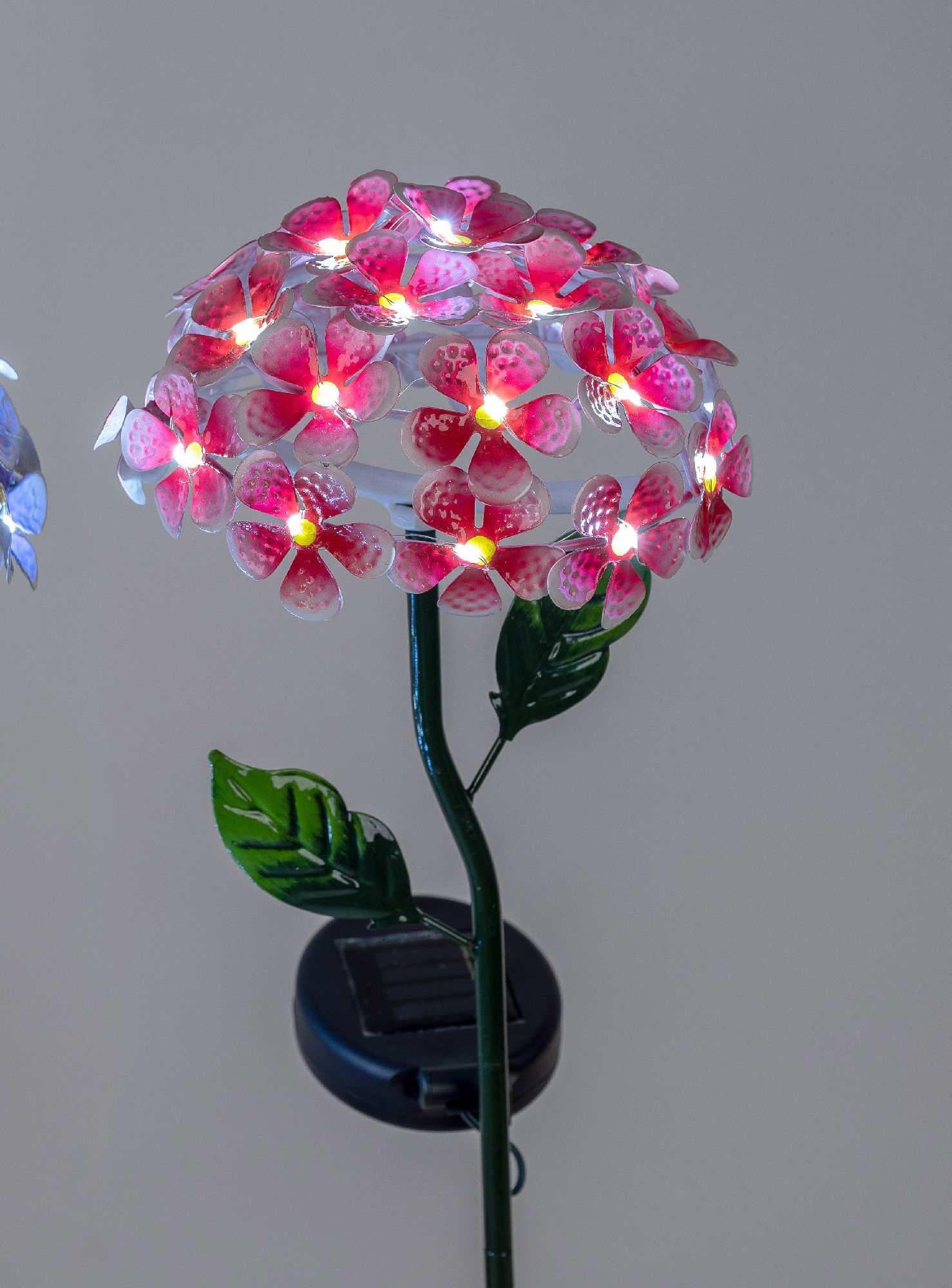 Dekorative Solarleuchte in Blumenform mit pinken Blüten und grünen Blättern, auf einem stabilen Stän