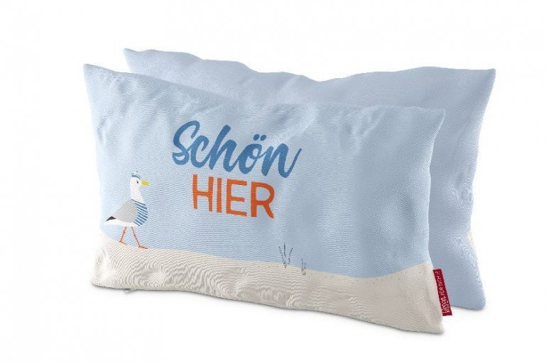 Zwei Kissen in Hellblau mit dem Aufdruck „Schön HIER“ und einer abgebildeten Möwe am unteren Rand.