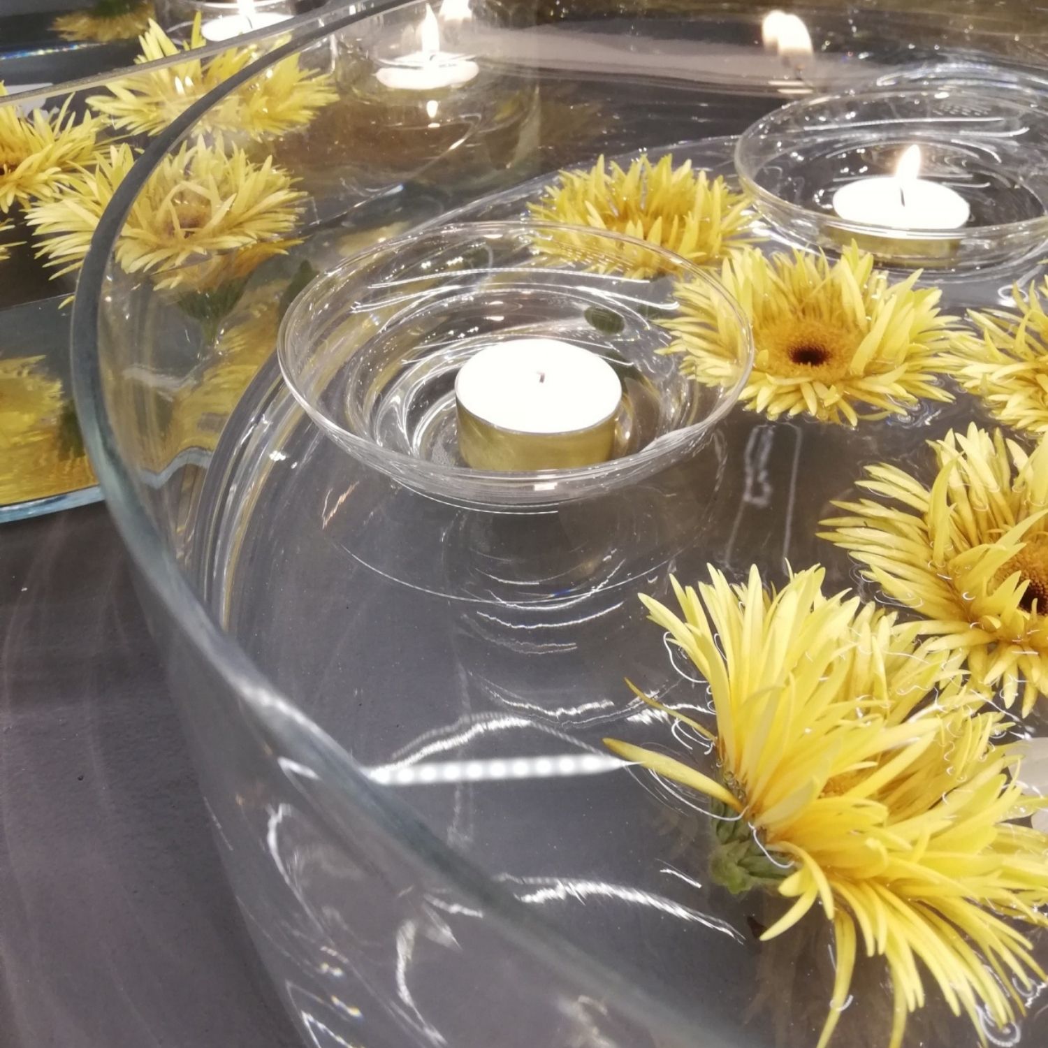 Glasschale mit Schwimmkerzen und Blüten dekoriert