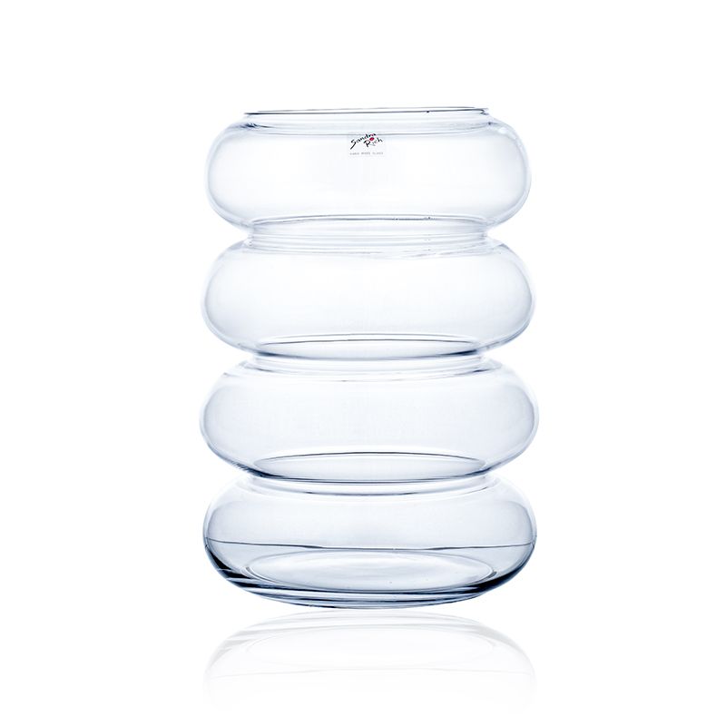 Transparente Glasvase mit vier übereinander gestapelten, runden Formen. Die Oberfläche ist glatt und glänzend.