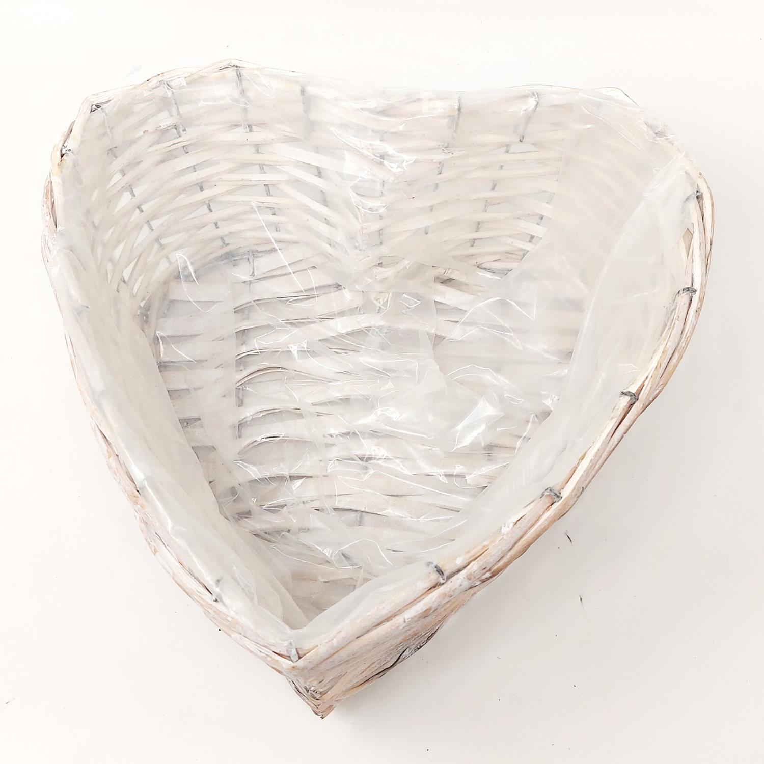 Ein herzförmiger Korb aus geflochtenem Material, innen mit einer transparenten Folie ausgelegt.
