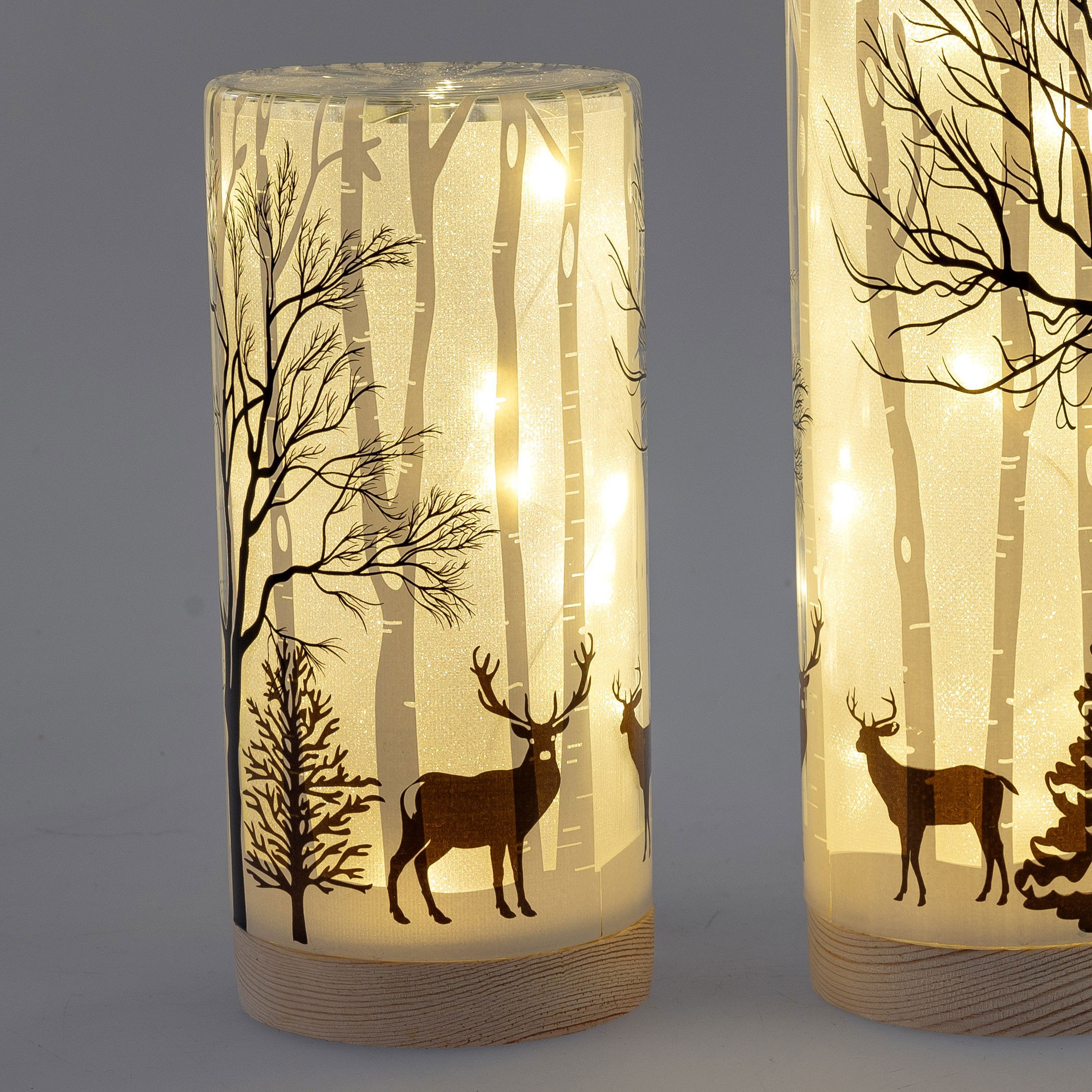 Zwei beleuchtete Laternen mit transparentem Design, verziert mit Bäumen und Rehen in einem Waldmotiv