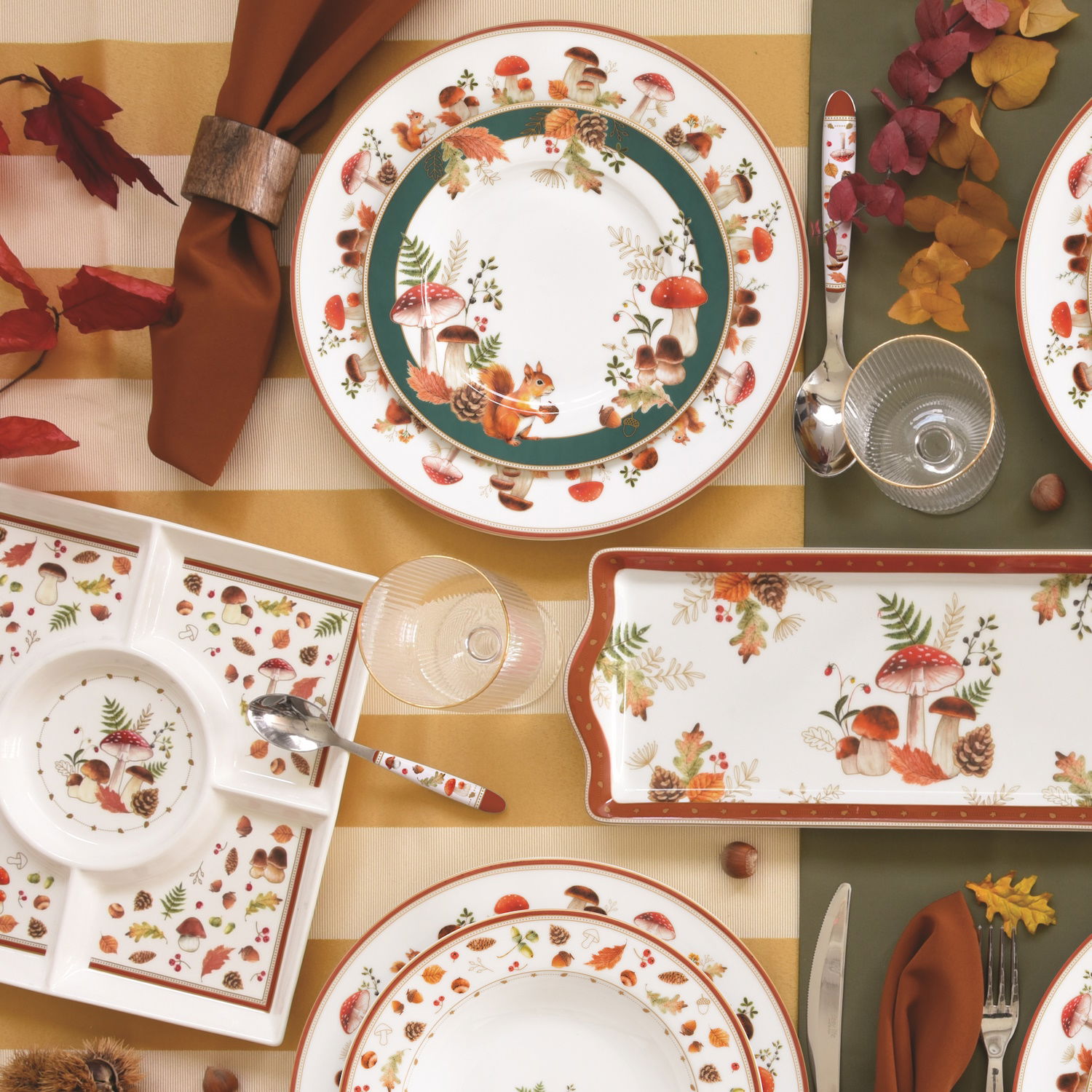 Tischgedeck mit Tellern, Besteck und herbstlichen Dekorationen