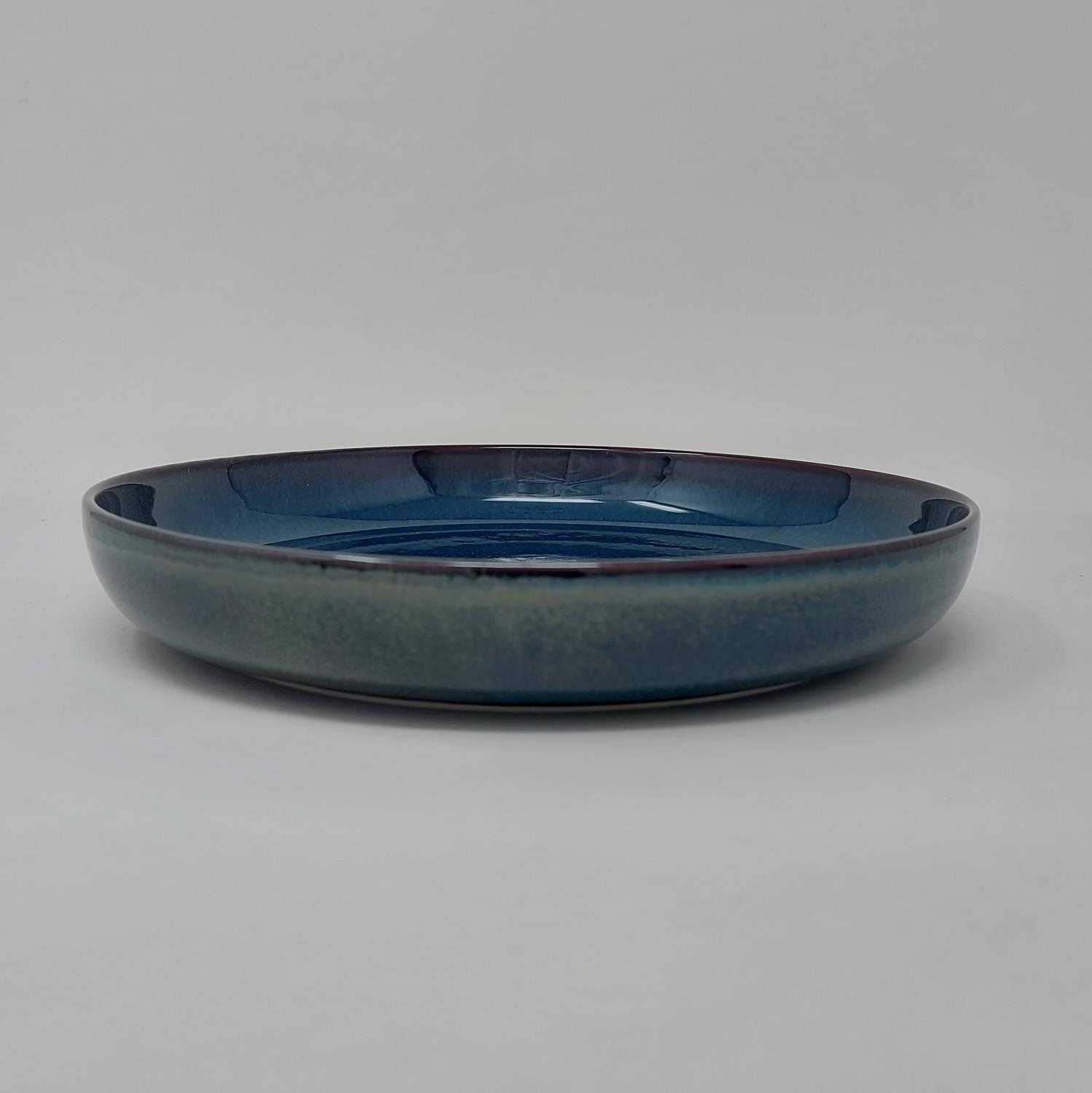 Flacher, runder Teller in Blau- und Grüntönen mit glatter Oberfläche und leicht gewölbtem Rand, vor neutralem Hintergrund.