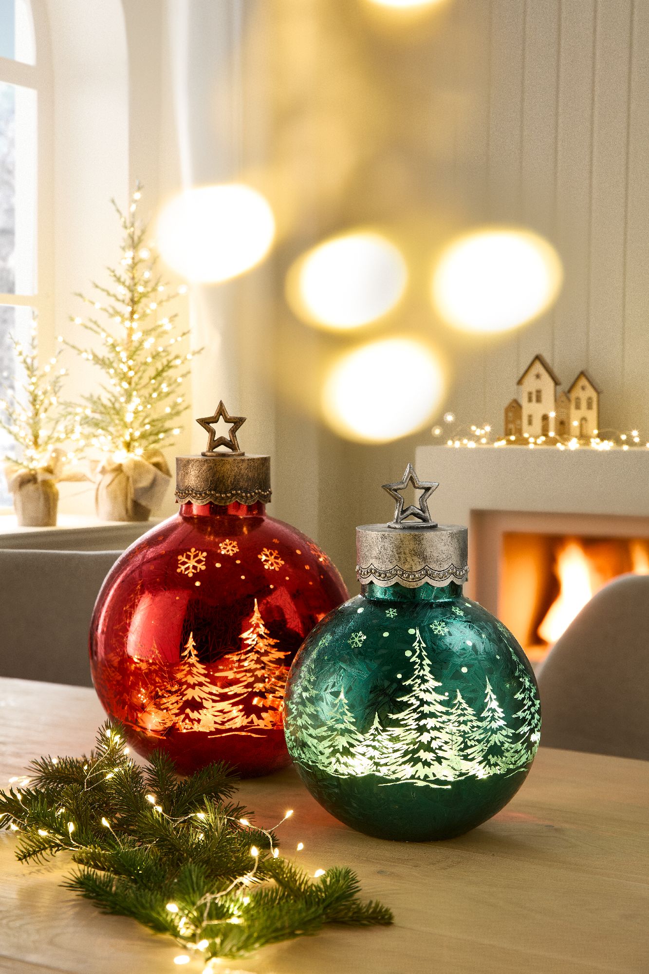 Zwei Weihnachtskugeln in Rot und Grün mit Schneeflocken- und Tannenbaum-Motiven stehen auf einem Tis