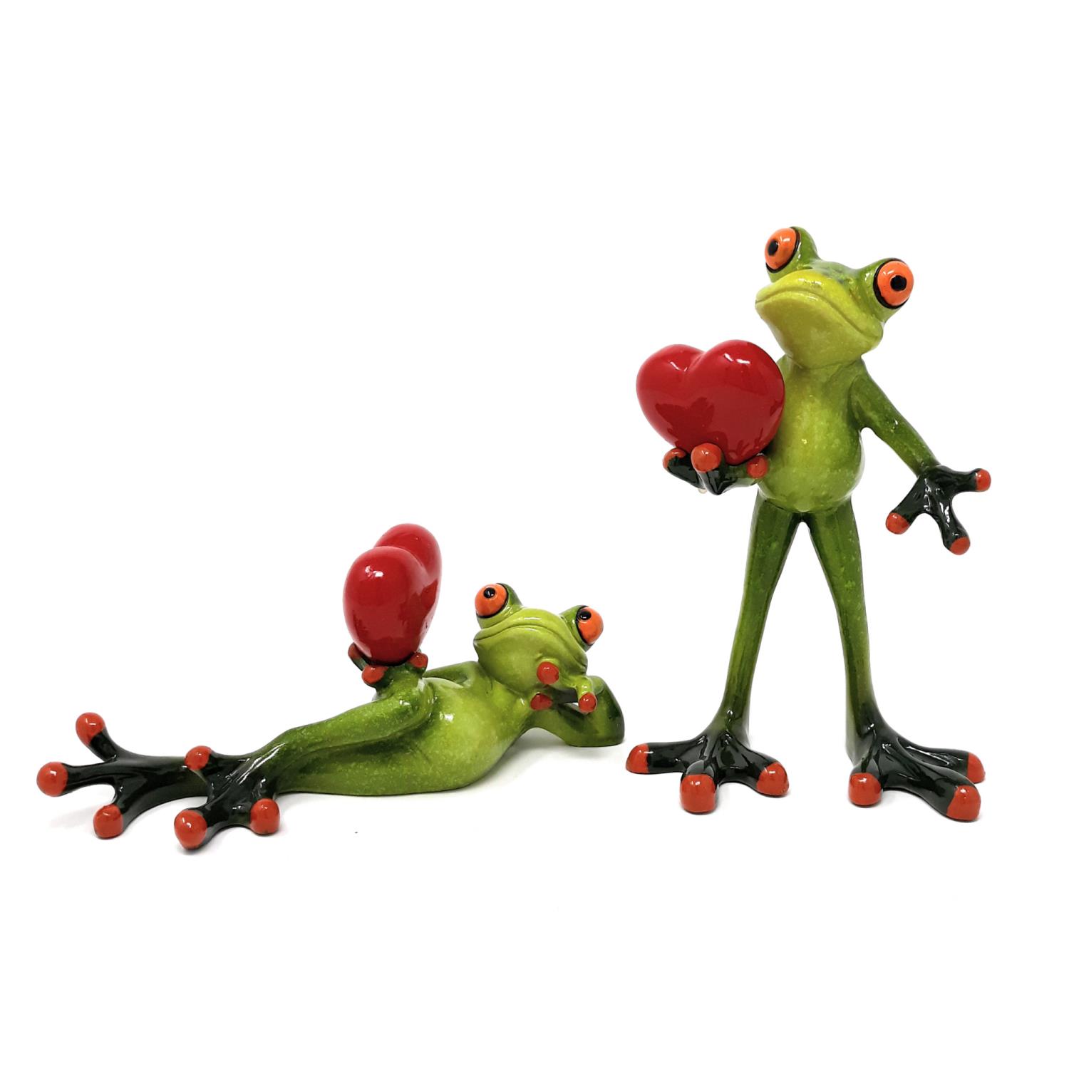 Zwei grüne Frösche mit roten Herzen in den Händen. Einer steht aufrecht, der andere liegt auf dem Boden.