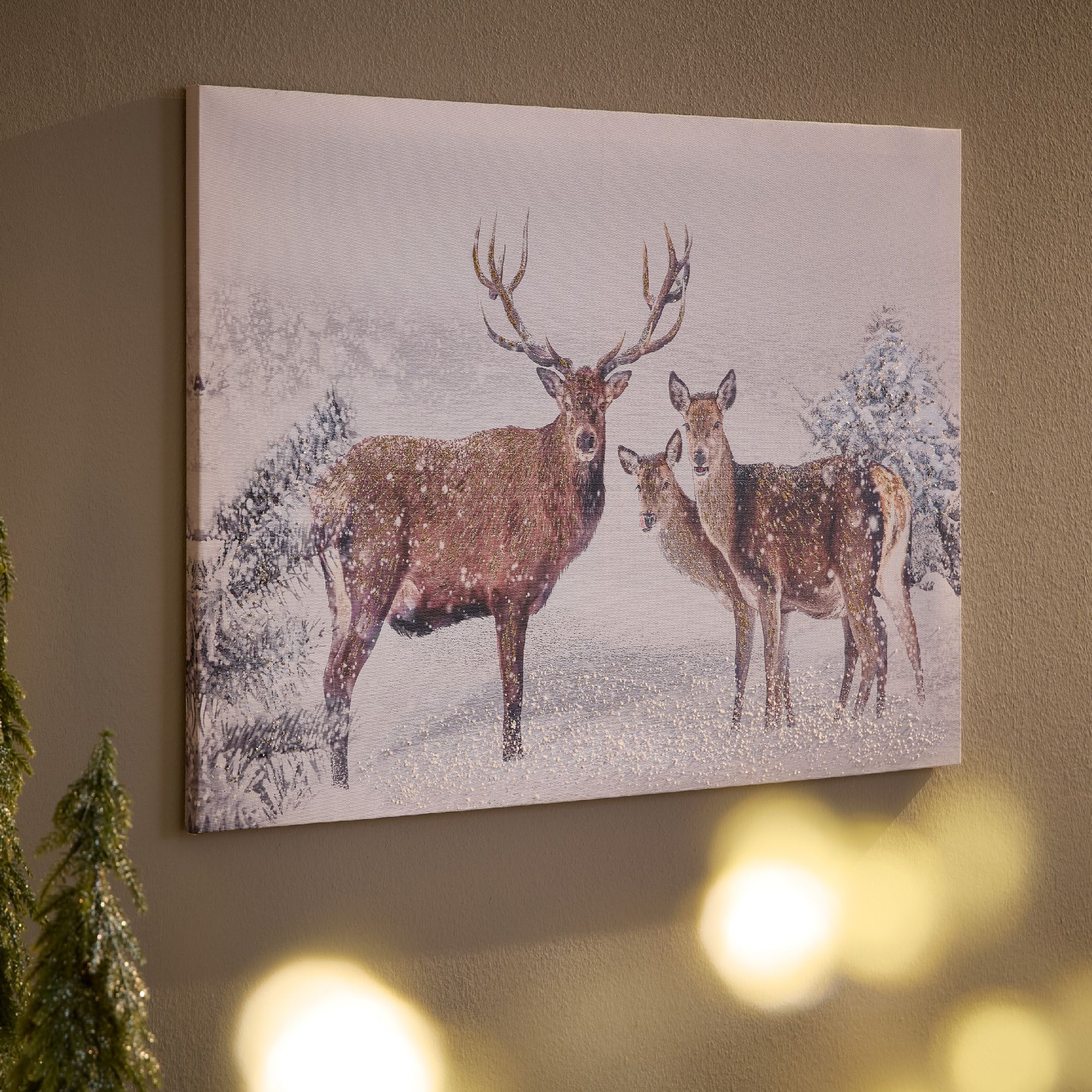 Ein Gemälde zeigt einen Hirsch und ein Reh im Schnee, umgeben von schneebedeckten Bäumen. Die Szene