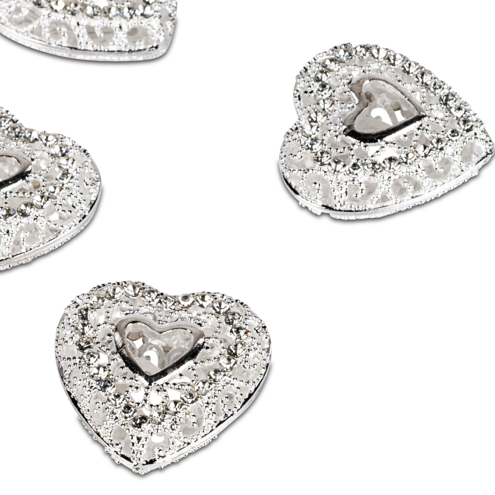 Vier silberne Herzformen mit glitzernden Verzierungen liegen auf einem hellen Hintergrund.