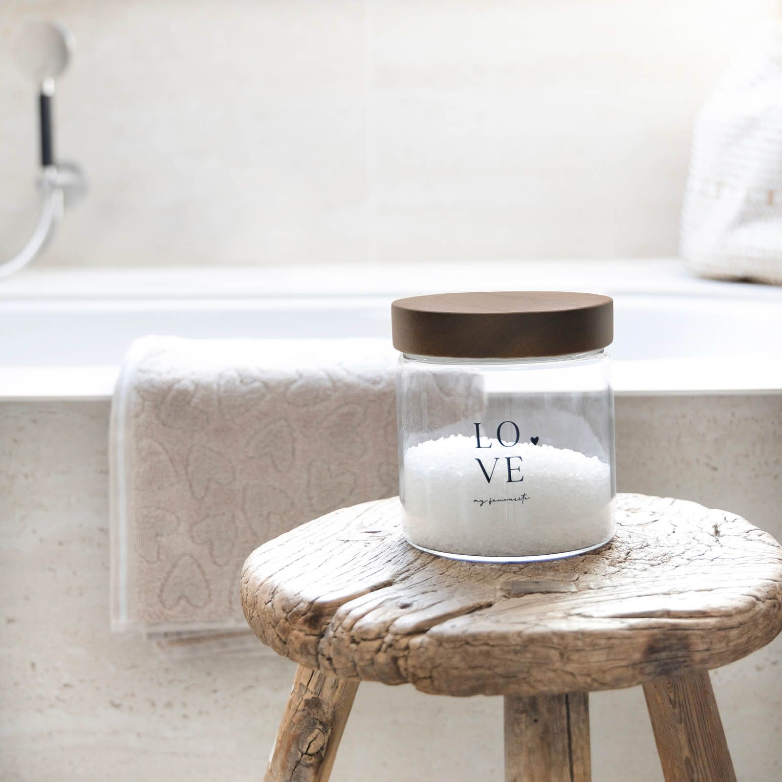 Ein Glasbehälter mit braunem Deckel steht auf einem Holzstuhl. Im Glas befindet sich weißes Salz. Im