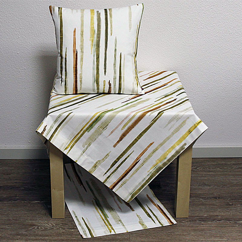 Ein Stuhl mit einem Kissen und einem Tischdecken, beide mit einem Muster aus senkrechten, farbigen Streifen auf weißem Hintergrund.