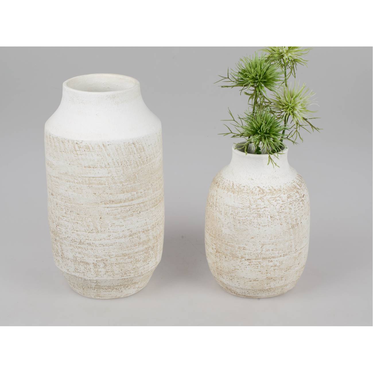 Zwei keramische Vasen in neutralen Farben, eine größere und eine kleinere, mit einer Pflanze in der kleineren Vase.