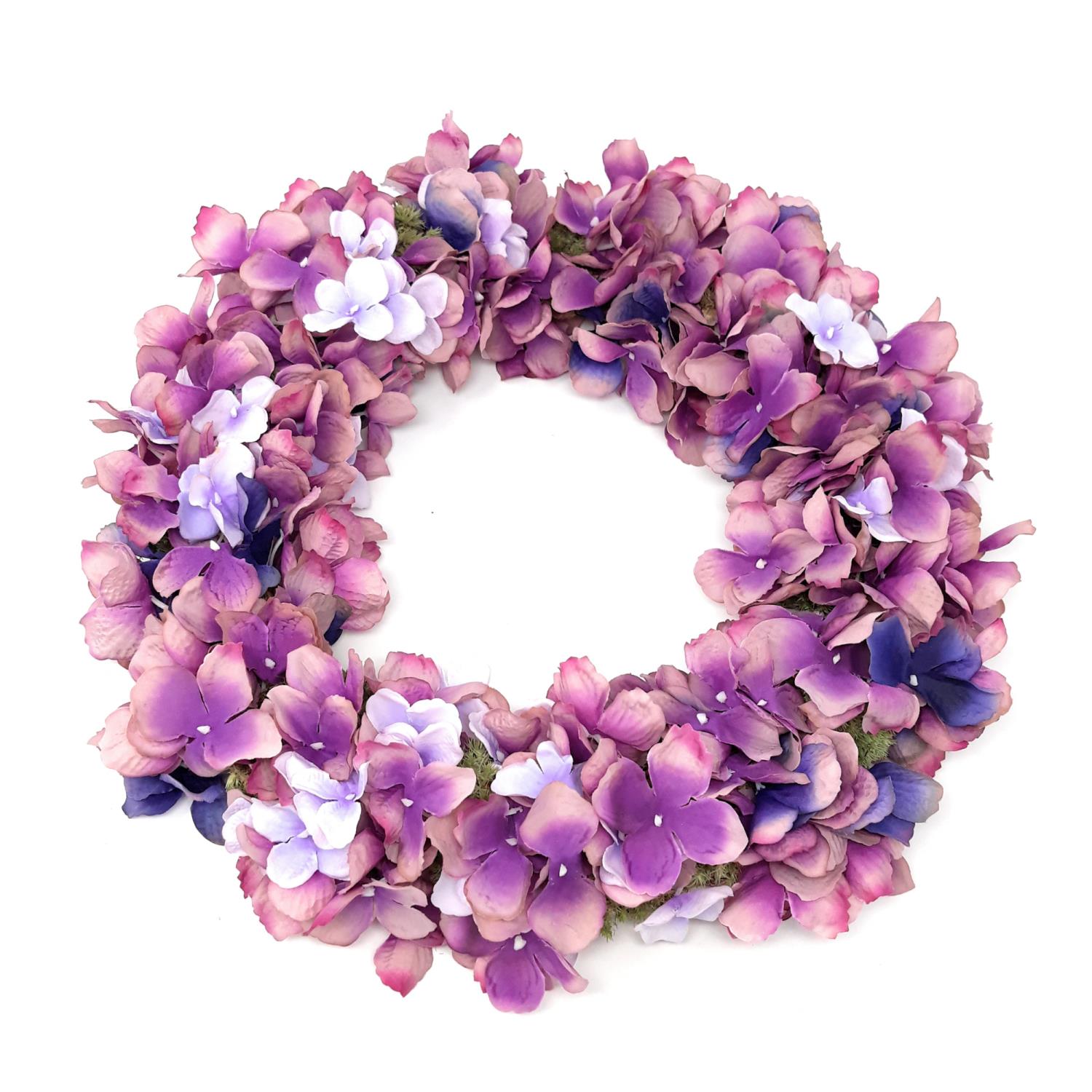 Ein runder Kranz aus lila und violetten Kunstblumen mit weißen Akzenten, in der Mitte offen.