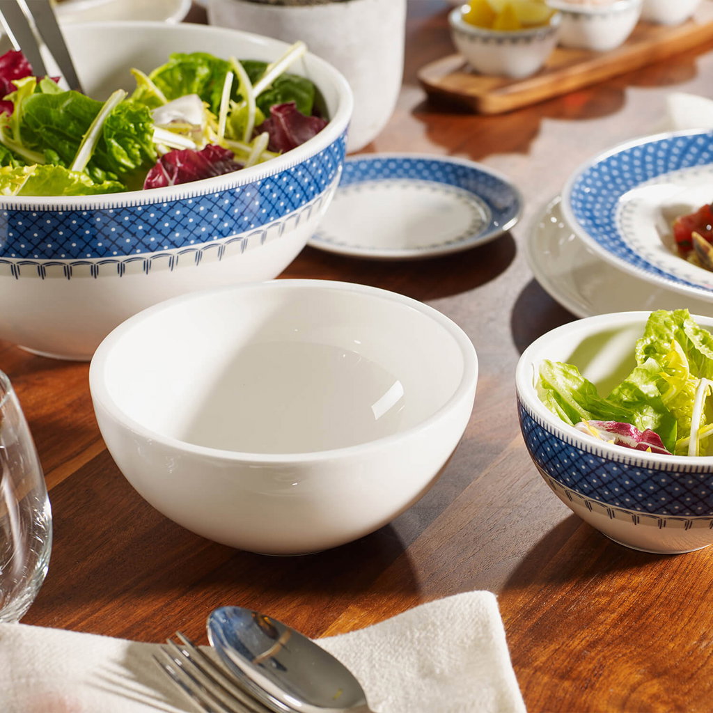 Tischgedeck mit verschiedenen Schalen, darunter eine große Salatschüssel und kleinere Schalen mit Sa