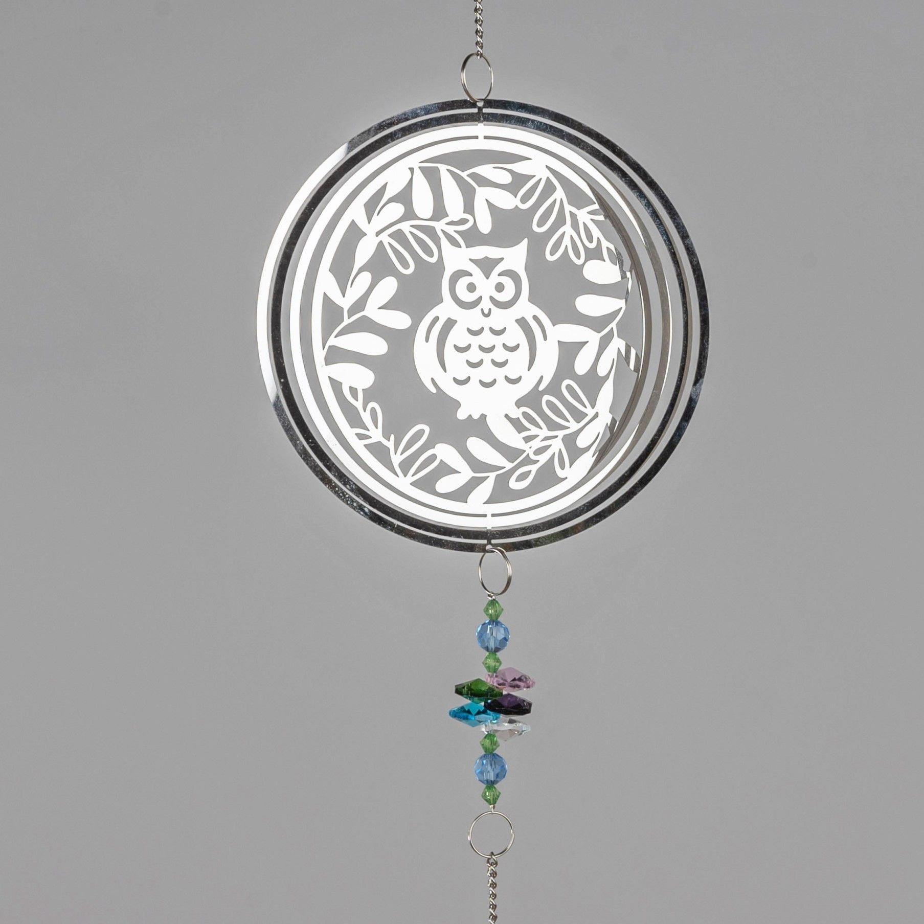 Dekoratives Windspiel mit einer weißen Eule und Blättern, darunter bunte Glasperlen, an einer Kette aufgehängt.