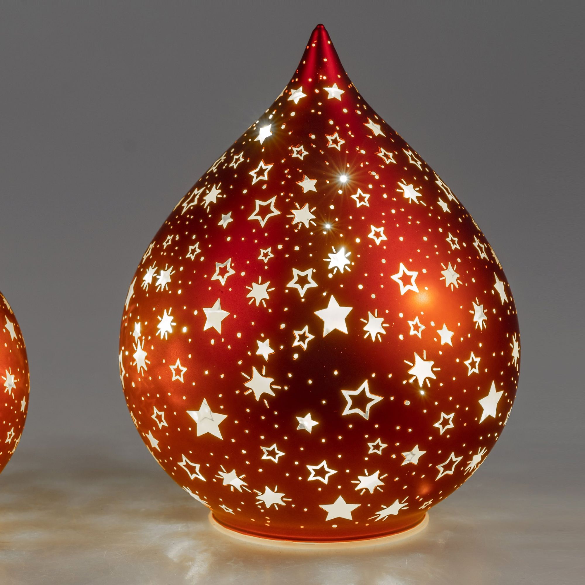 Rote, tropfenförmige Lampe mit durchbrochenem Sternenmuster, die von innen beleuchtet ist und einen