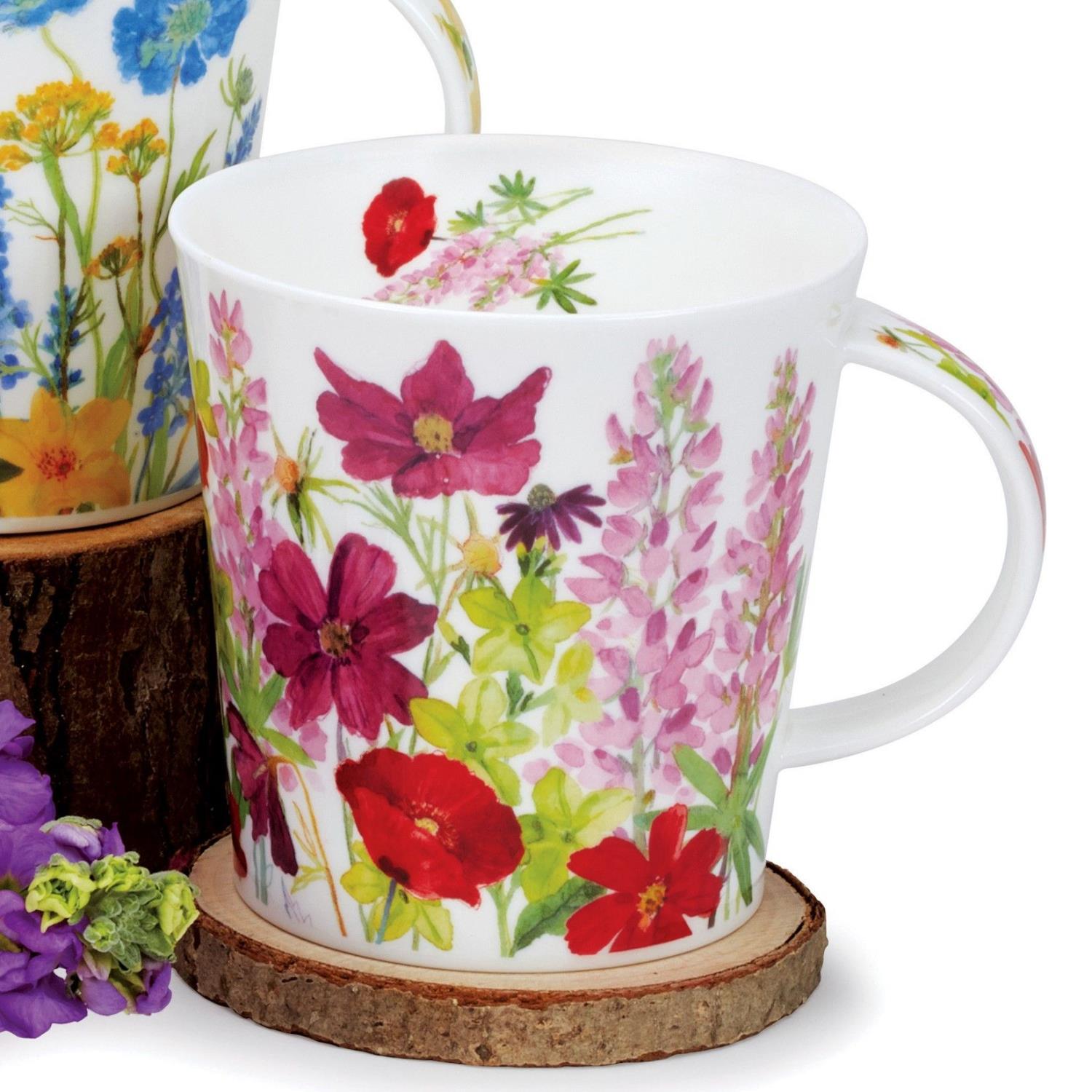 Zwei Tassen mit bunten Blumenmustern stehen auf einem Holzuntersetzer. Eine Tasse hat blaue und gelbe Blumen, die andere pinke und rote.