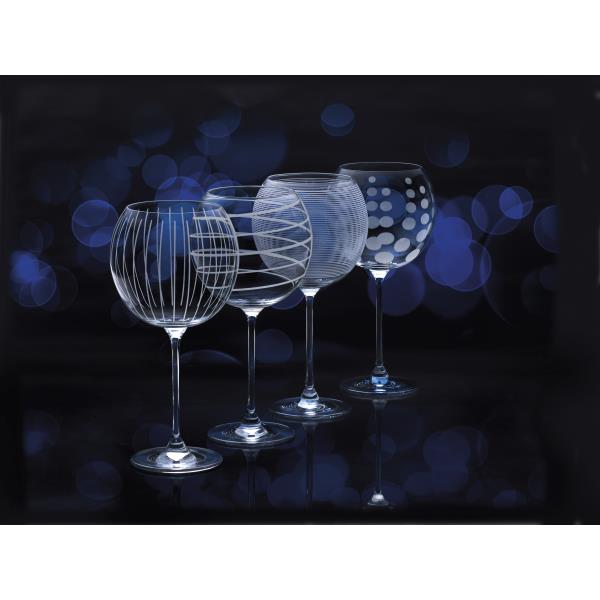 Vier elegante Weingläser mit unterschiedlichen Mustern stehen vor einem dunklen Hintergrund mit blauen Lichtpunkten.