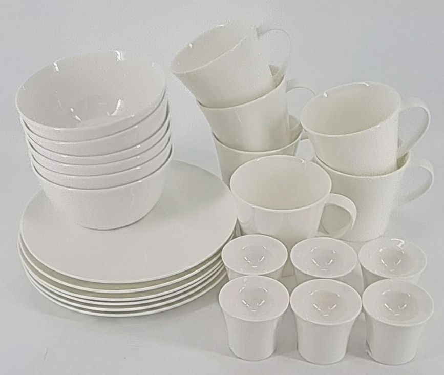 Ein Set aus weißen Tellern, Schalen, Tassen und Bechern, unterschiedlich gestapelt und angeordnet.