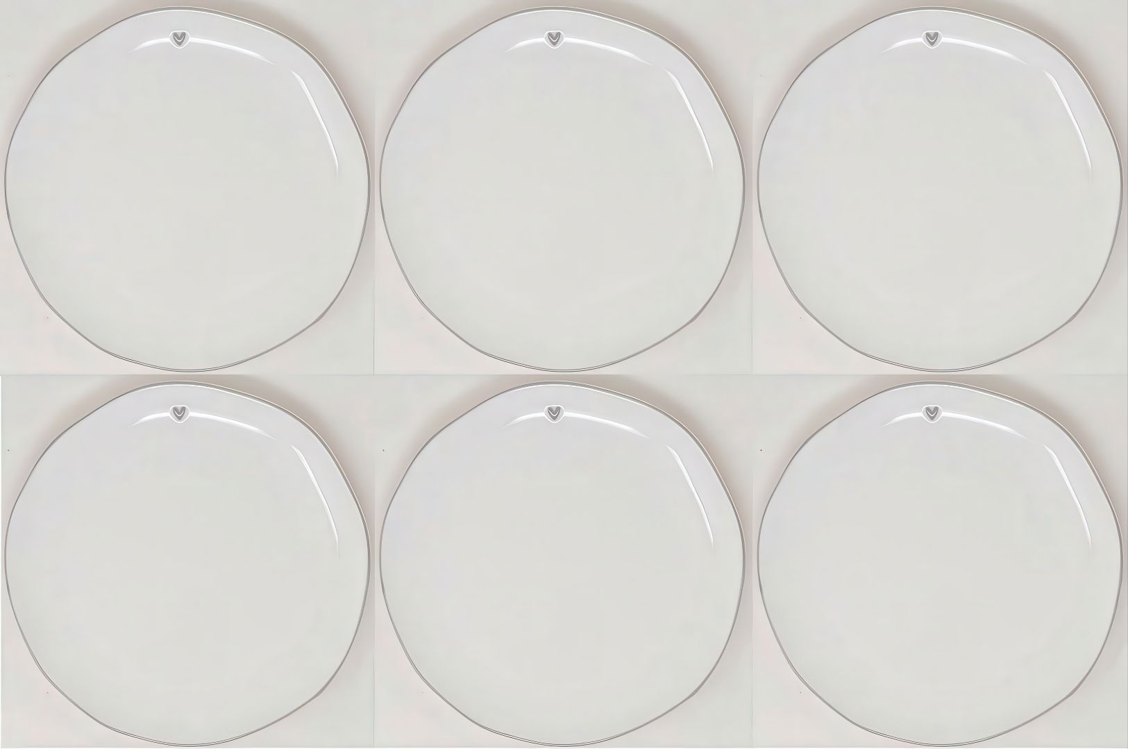 Sechs weiße, runde Teller mit leicht gewelltem Rand und einem kleinen Herzsymbol an der oberen Kante