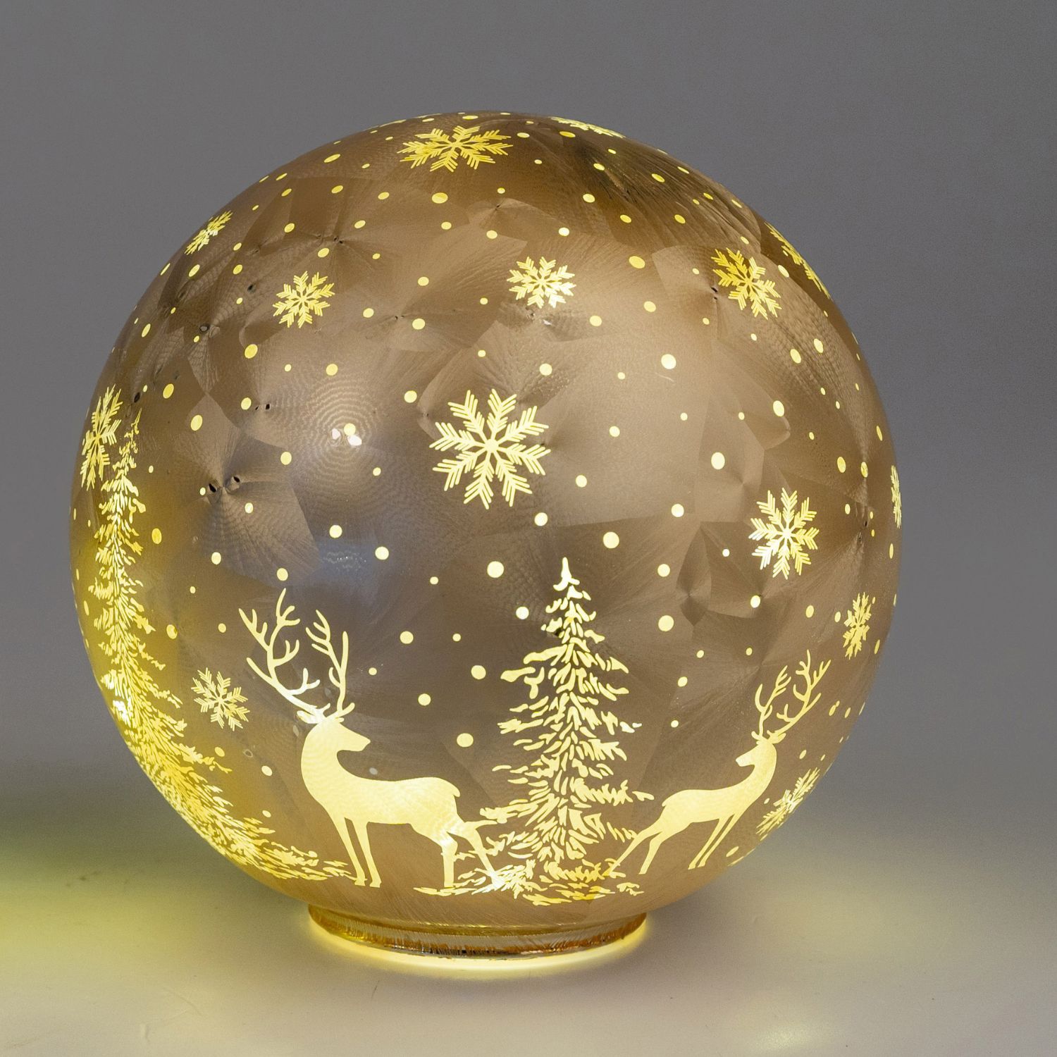 Leuchtende Glaskugel mit Schneeflocken, Tannen und zwei Hirschen auf grauem Hintergrund