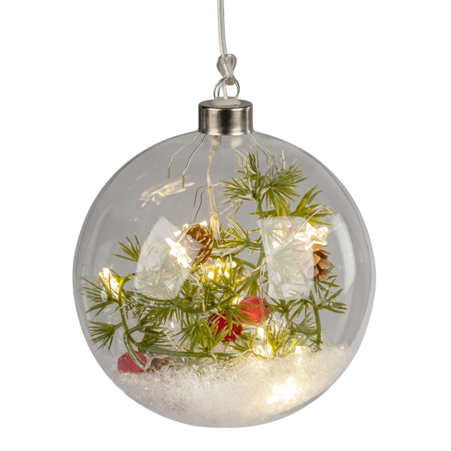 Glaskugel mit Kunstschnee, Tannenzweigen, kleinen Zapfen und warmweißen Lichtern