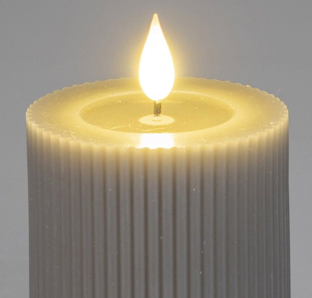 Eine weiße, gerippte Kerze mit einer flackernden, leuchtenden Flamme in der Mitte auf einem neutralen Hintergrund.