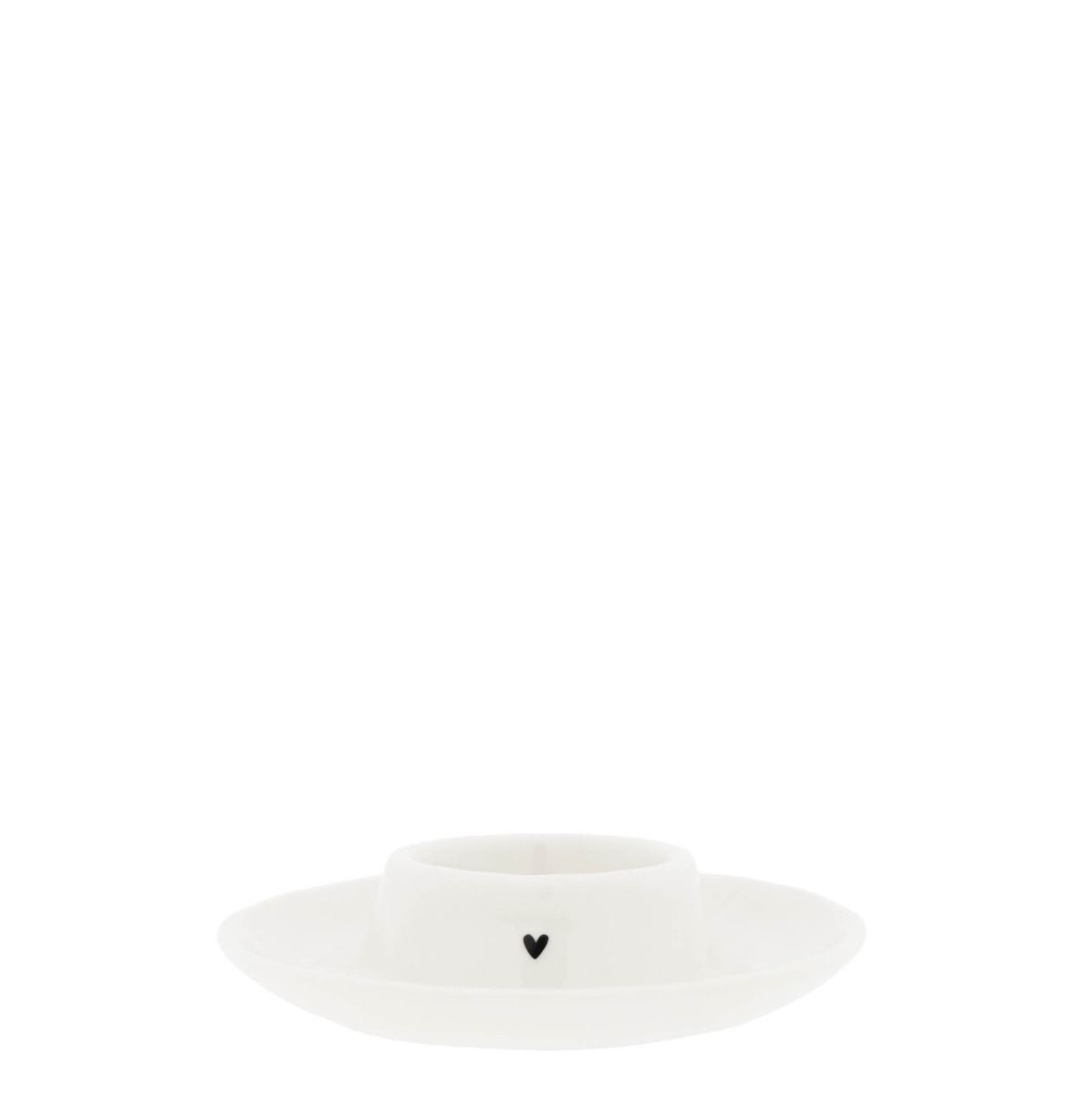 Weißer Kerzenhalter mit flacher Unterlage und einer kleinen schwarzen Herz-Dekoration.
