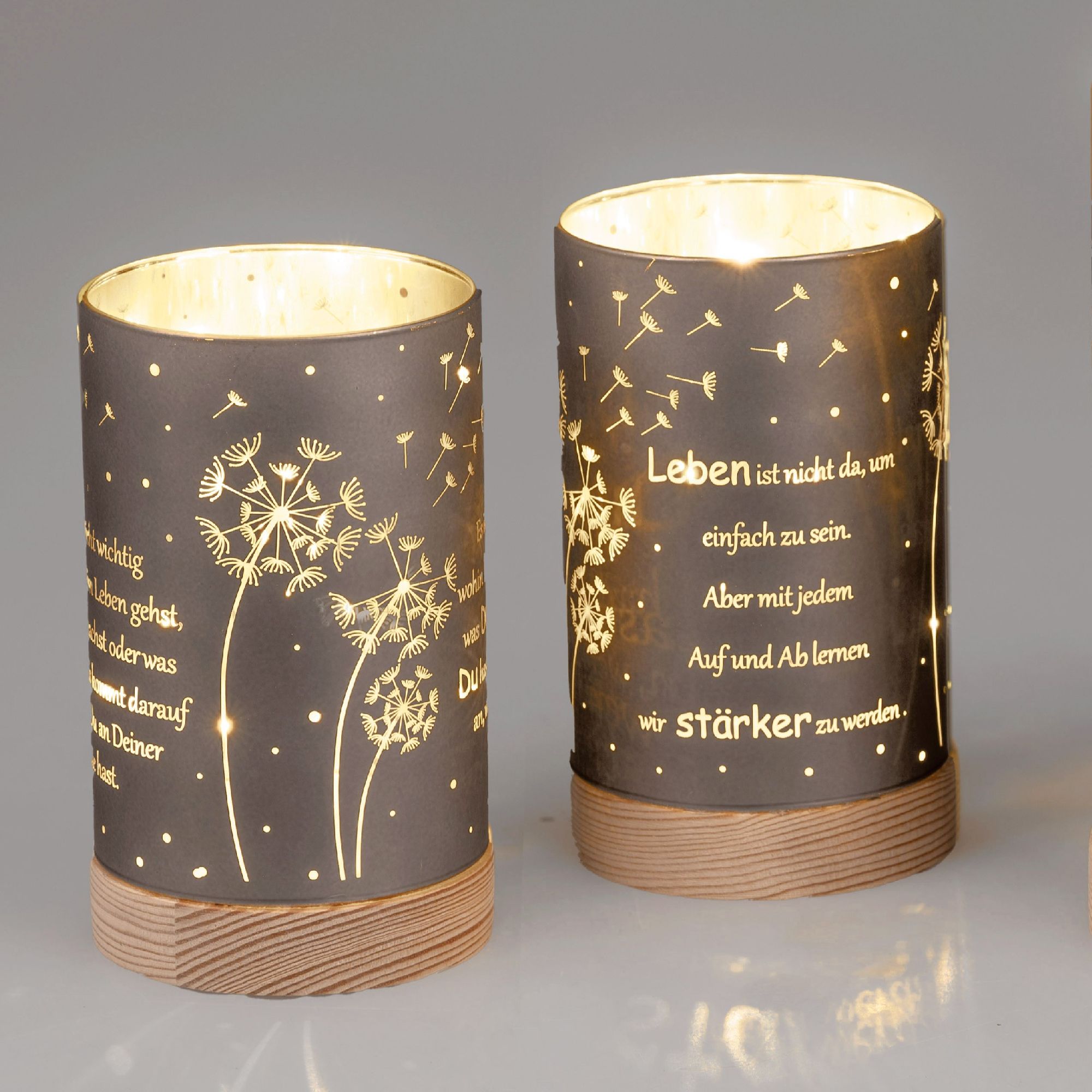 Zwei dekorative Laternen mit schwarzem Papier und goldenen Schriftzügen, verziert mit Pusteblumen-Motiven.