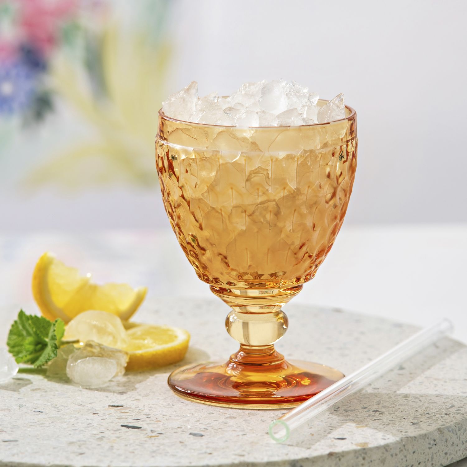 Ein orangefarbener Becher mit Eis und Zitronenscheiben auf einem Tisch