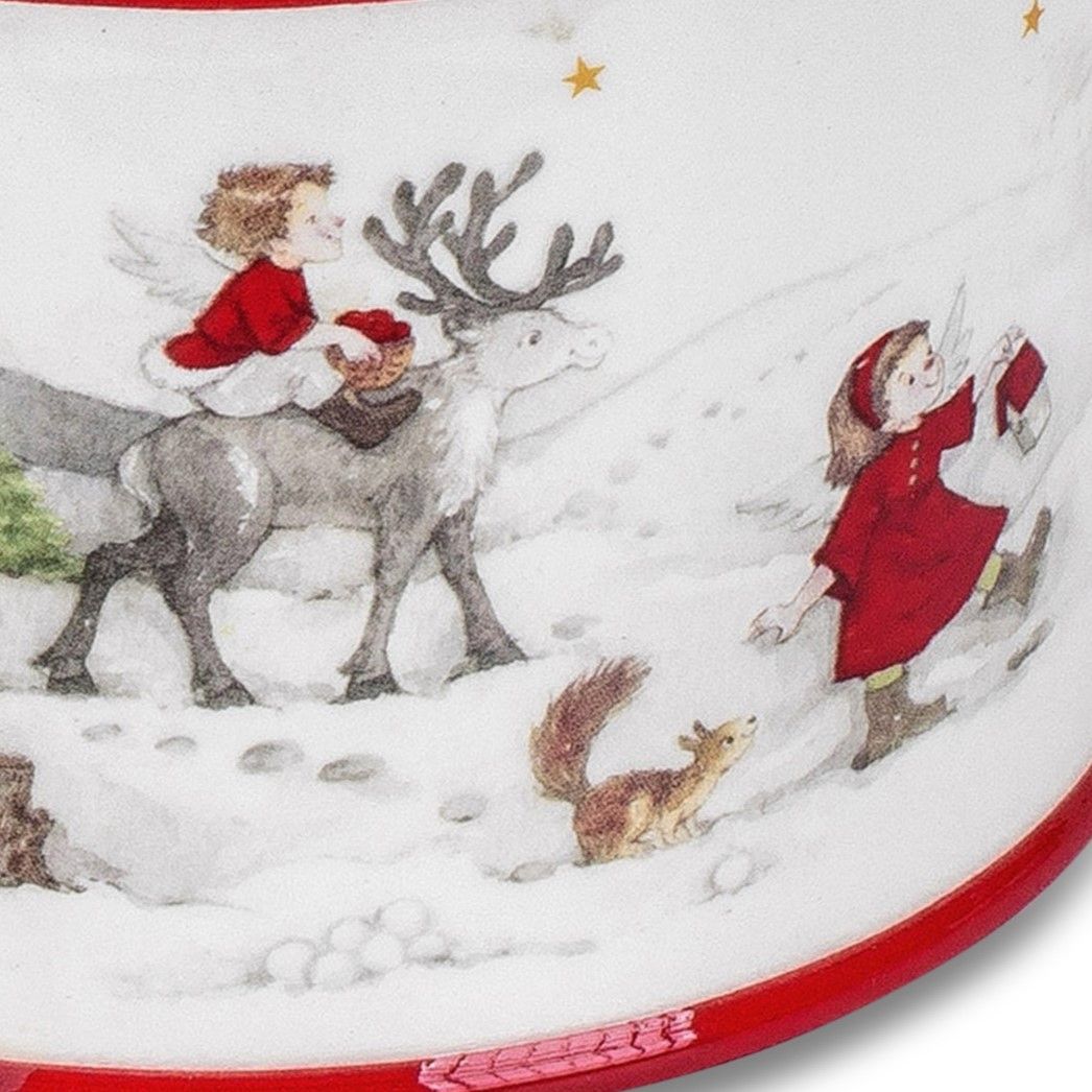 Ein Engel in rotem Gewand reitet auf einem Rentier durch den Schnee, während ein Mädchen mit einem G