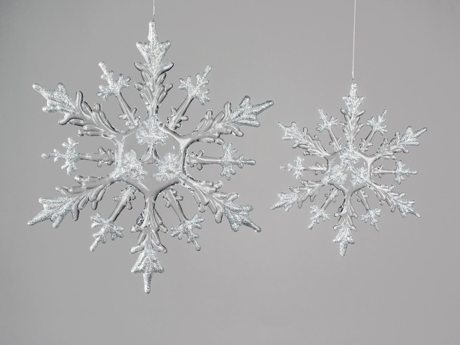 Zwei glitzernde Schneeflocken in Silber hängen vor einem grauen Hintergrund, eine größer als die and