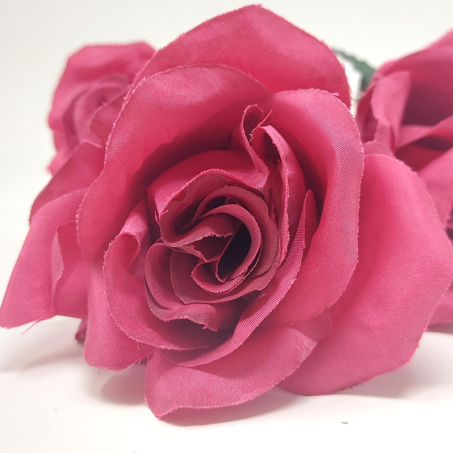 Drei pinkfarbene Stoffrosen mit detaillierten Blütenblättern auf hellem Hintergrund.