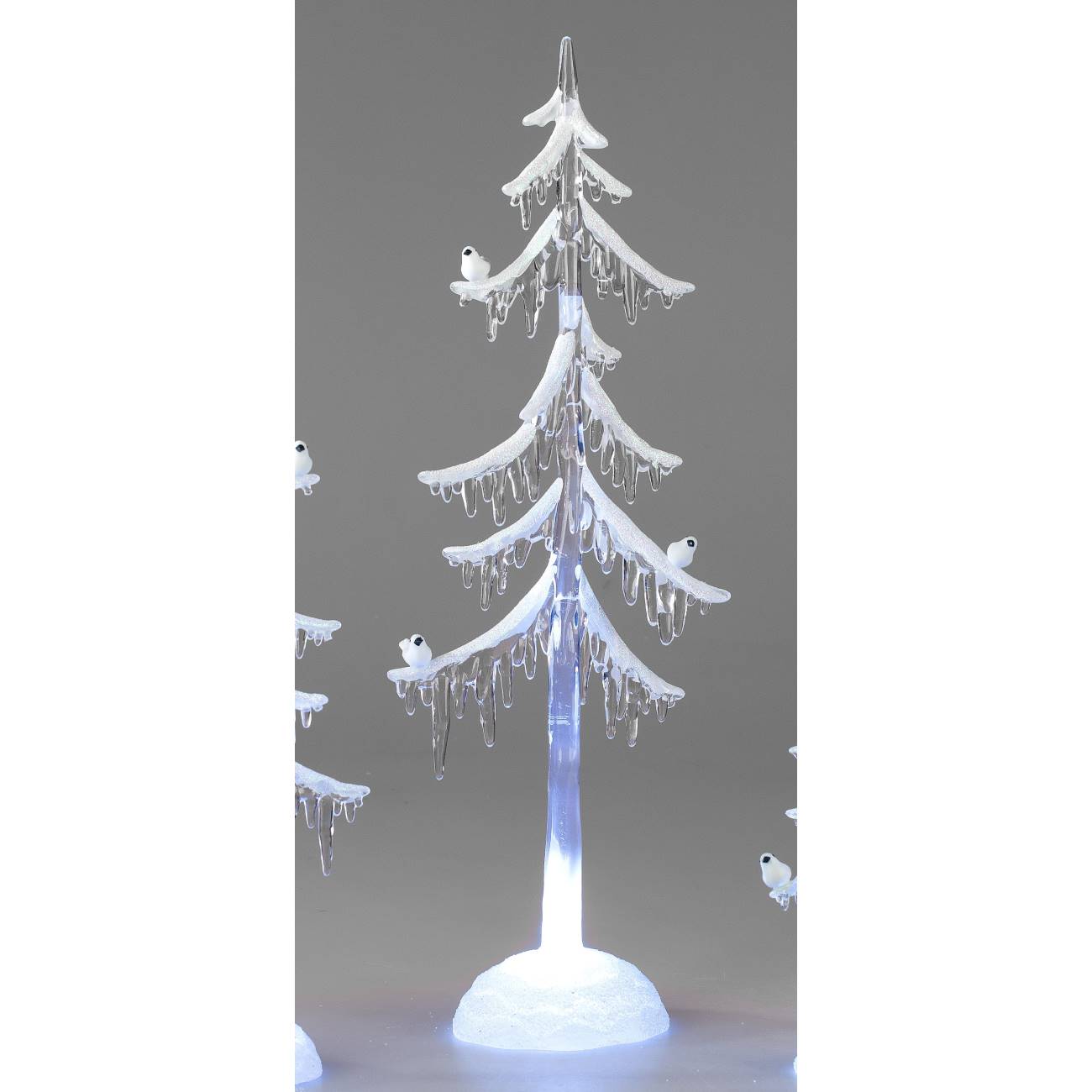 Ein künstlicher Weihnachtsbaum mit weißen, glitzernden Ästen und kleinen Vögeln, der von unten beleu