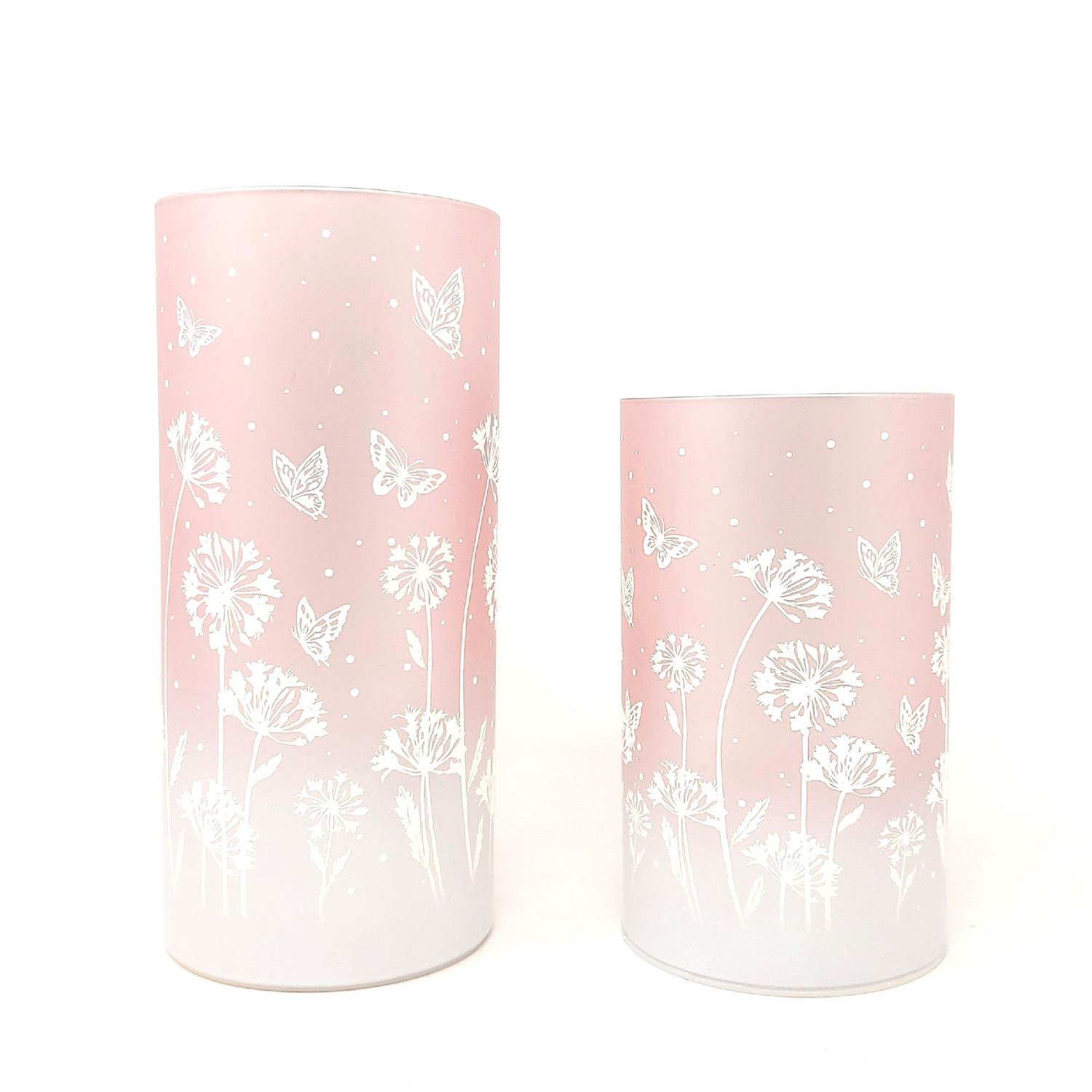 Zwei zylindrische Objekte in Rosa mit weißen Blumen- und Schmetterlingsmotiven, eines größer als das andere.