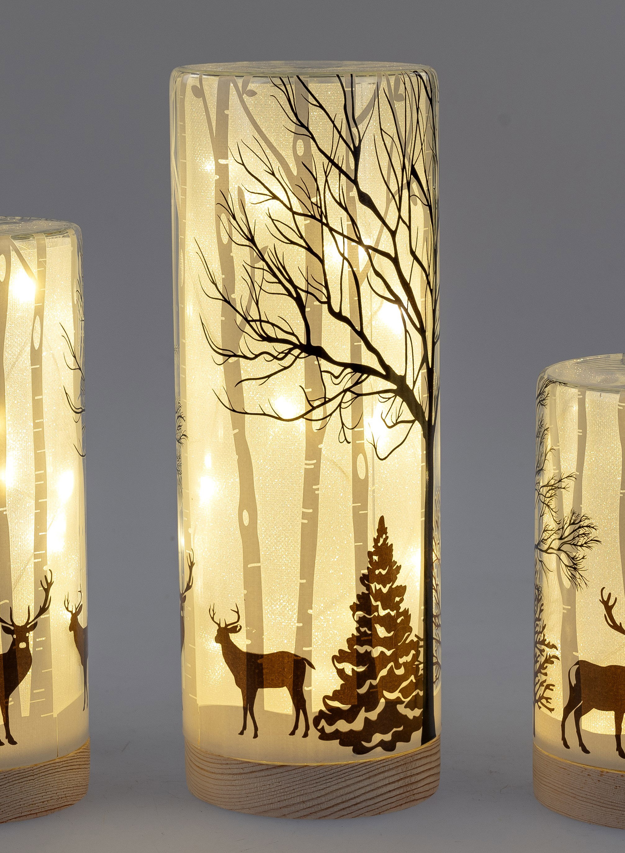 Drei beleuchtete Laternen mit transparentem Design, verziert mit Bäumen, Rehen und einem Tannenbaum