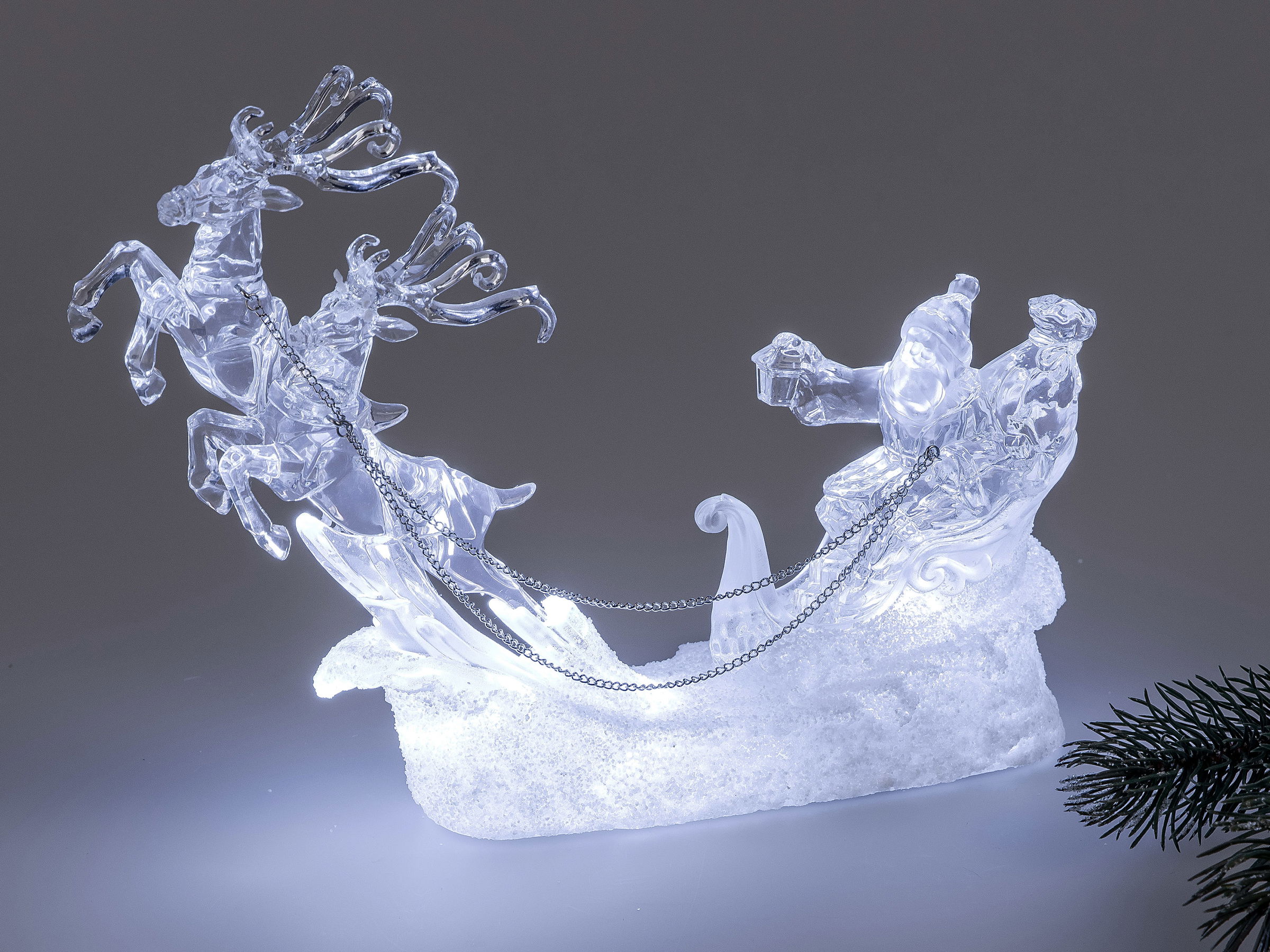 Durchsichtige Weihnachtsdekoration mit einem Schlitten, zwei Rentieren und einer Figur, die ein Gesc