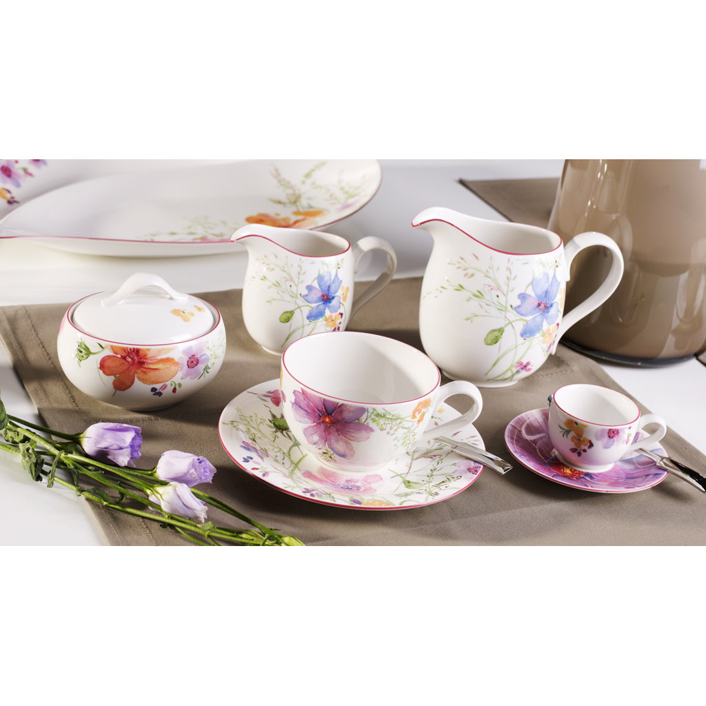 Ein Set aus Porzellan mit bunten Blumenmotiven, bestehend aus Tassen, Untertassen, einer Kanne und einer Zuckerdose.
